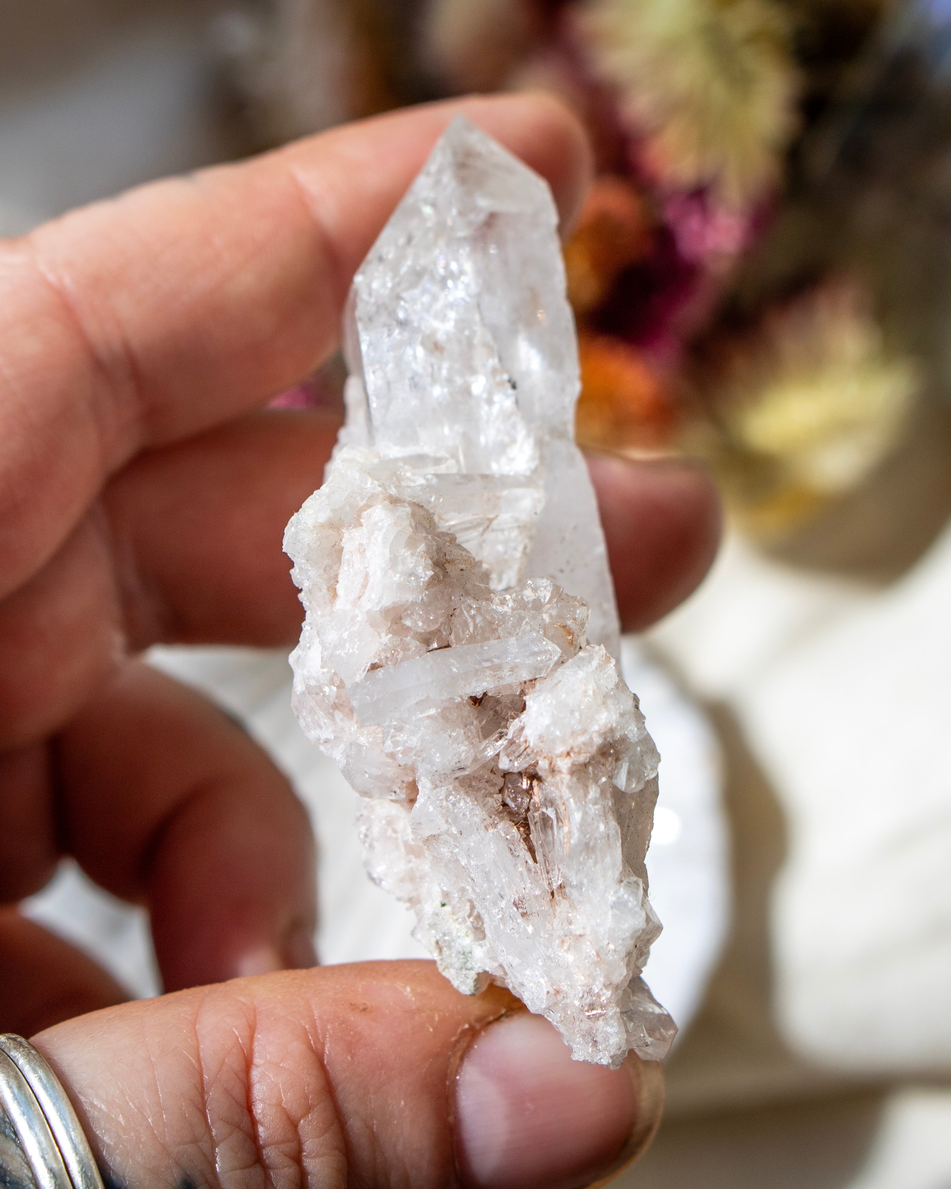 Clear crystal held in a hand with a blurred natural background