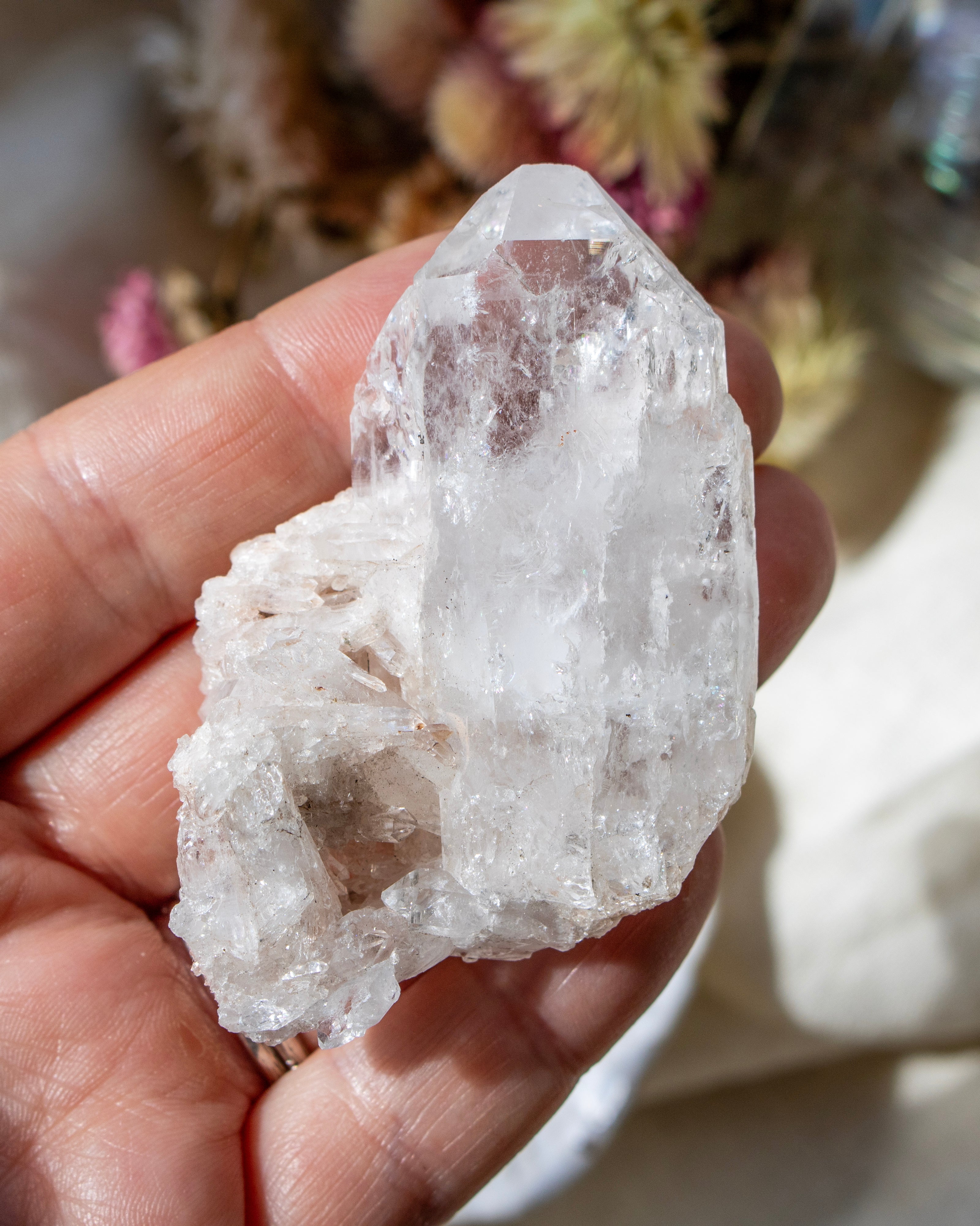 Clear crystal held in a hand with a blurred natural background