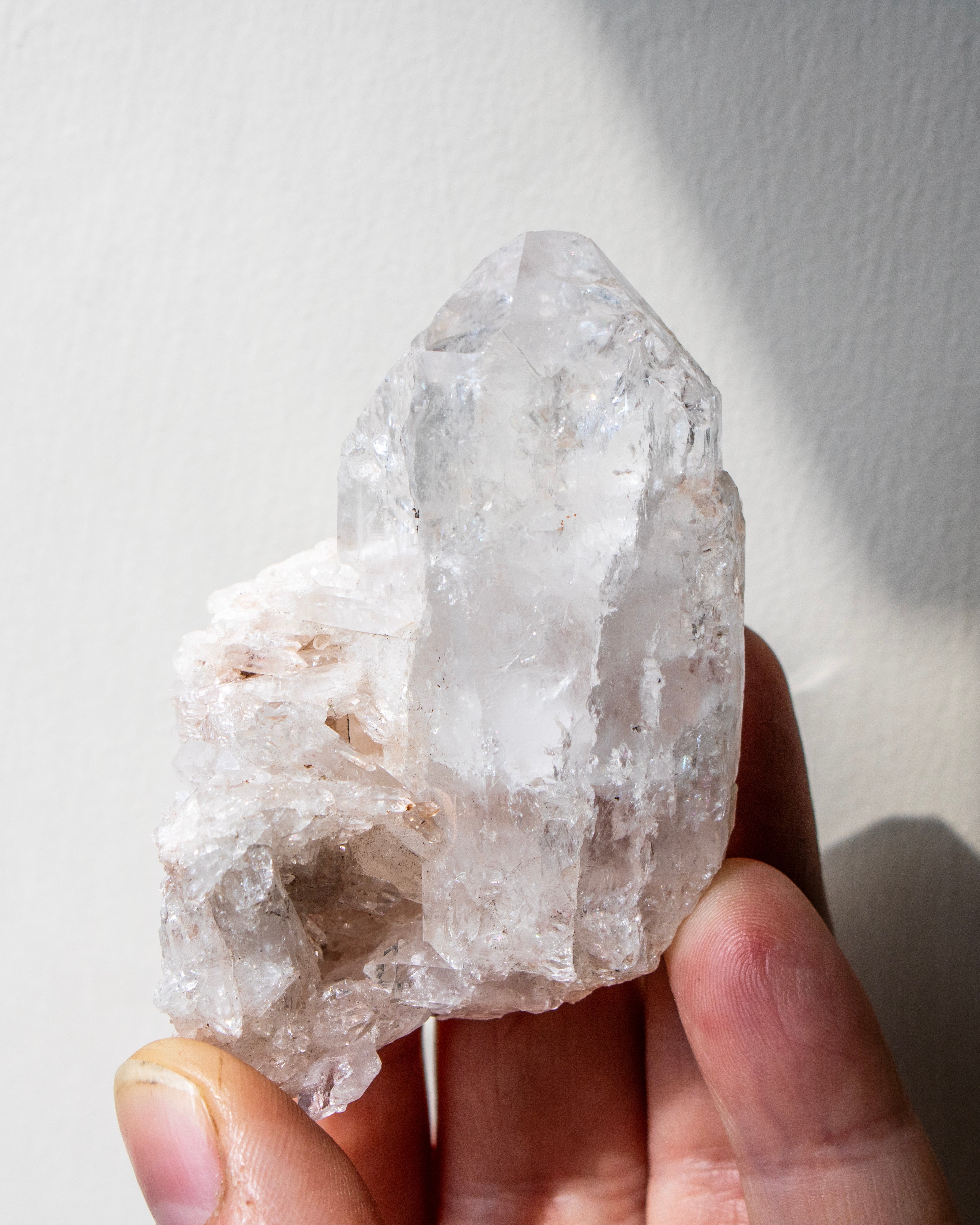 Clear crystal held in a hand against a white background