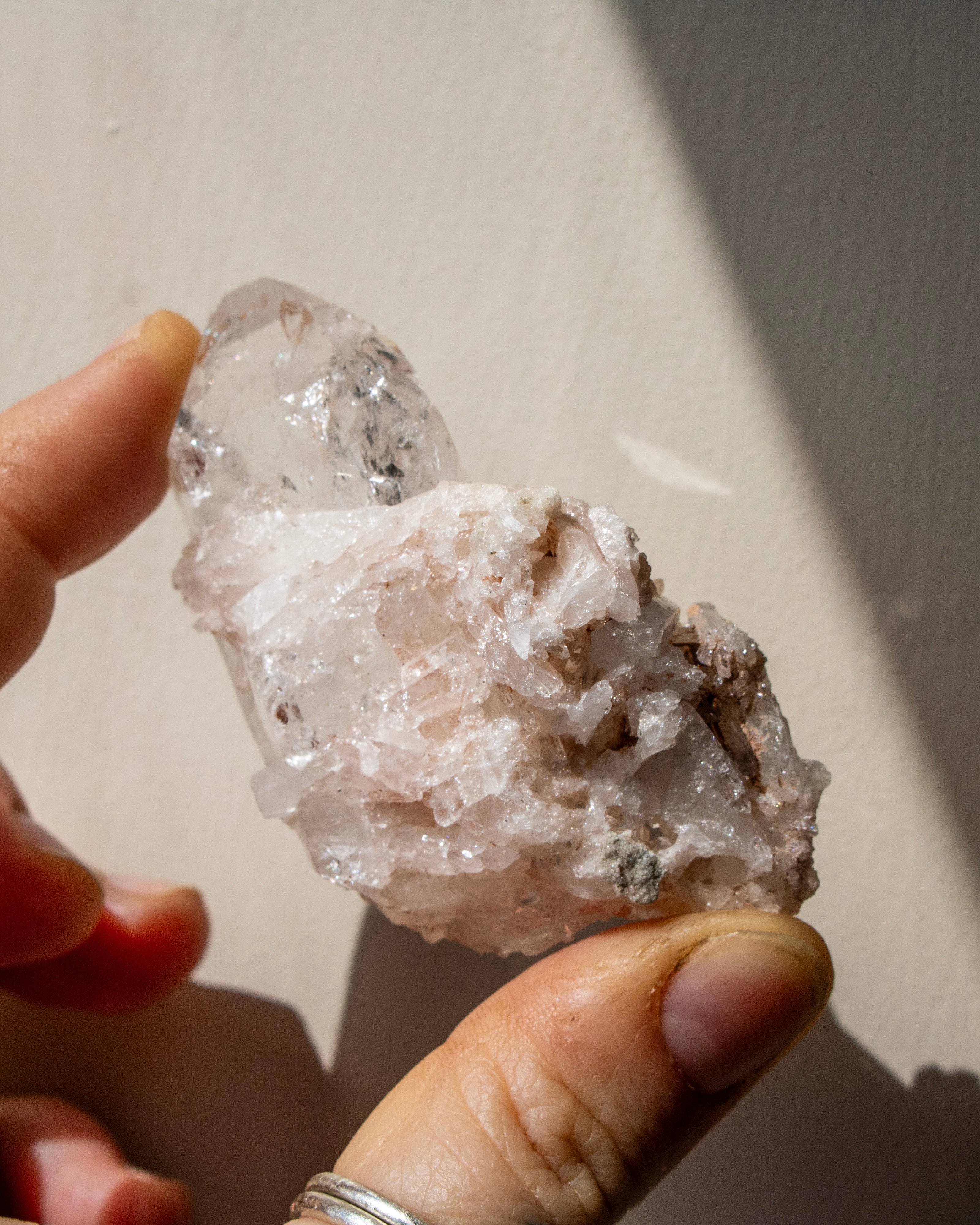 Hand holding a clear crystal rock against a neutral background
