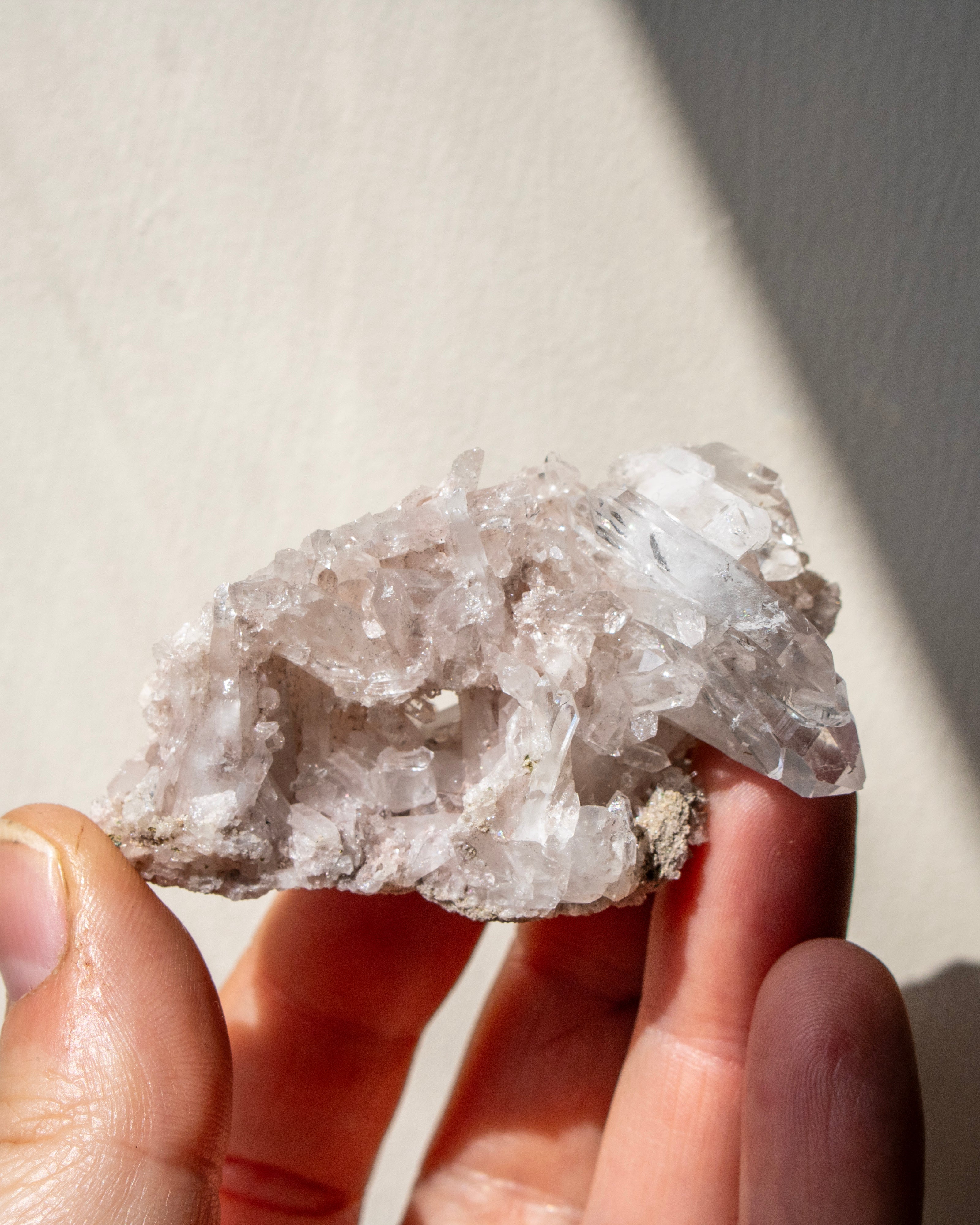 Hand holding a crystal with a blurred natural background