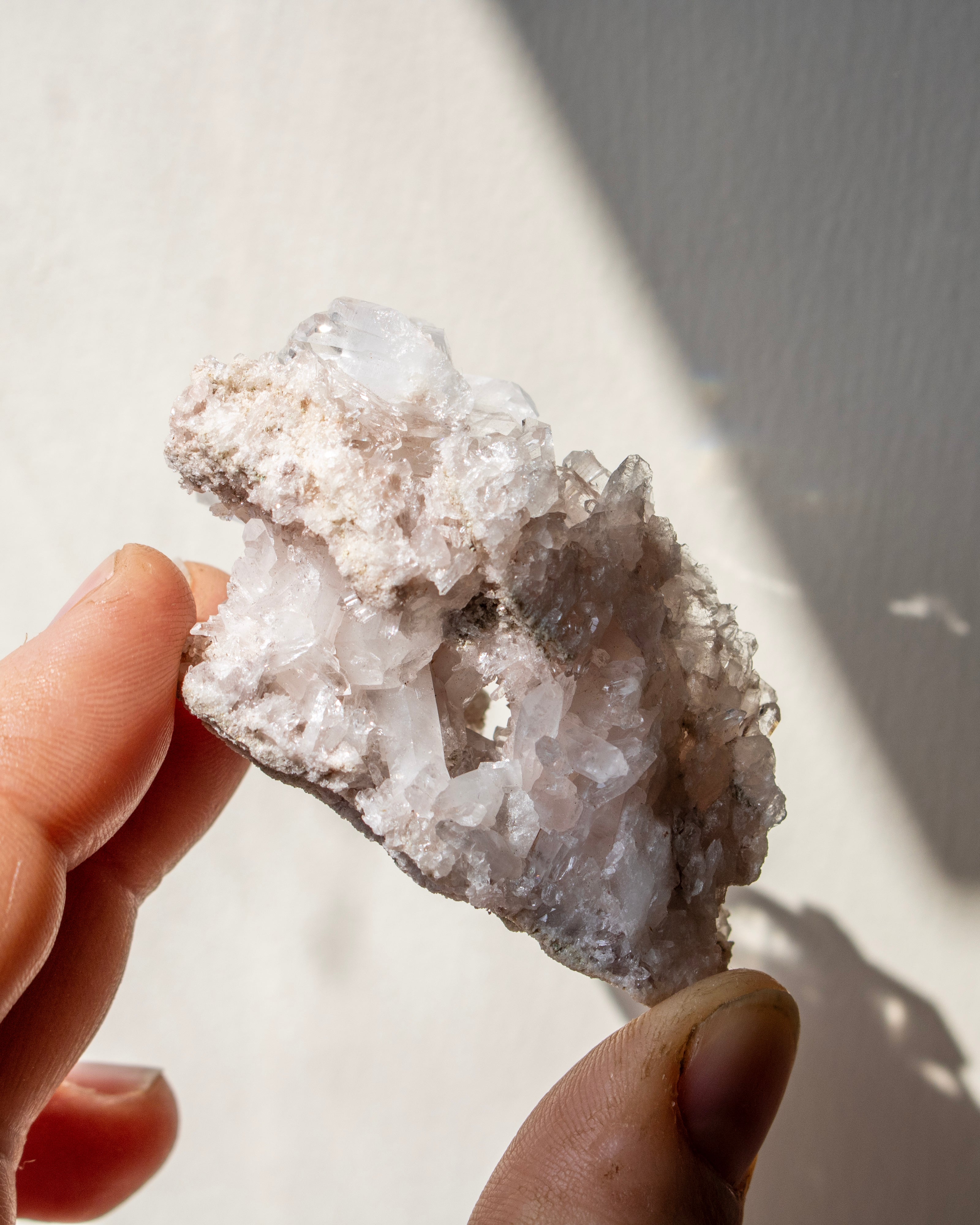 Hand holding a crystal with a blurred natural background