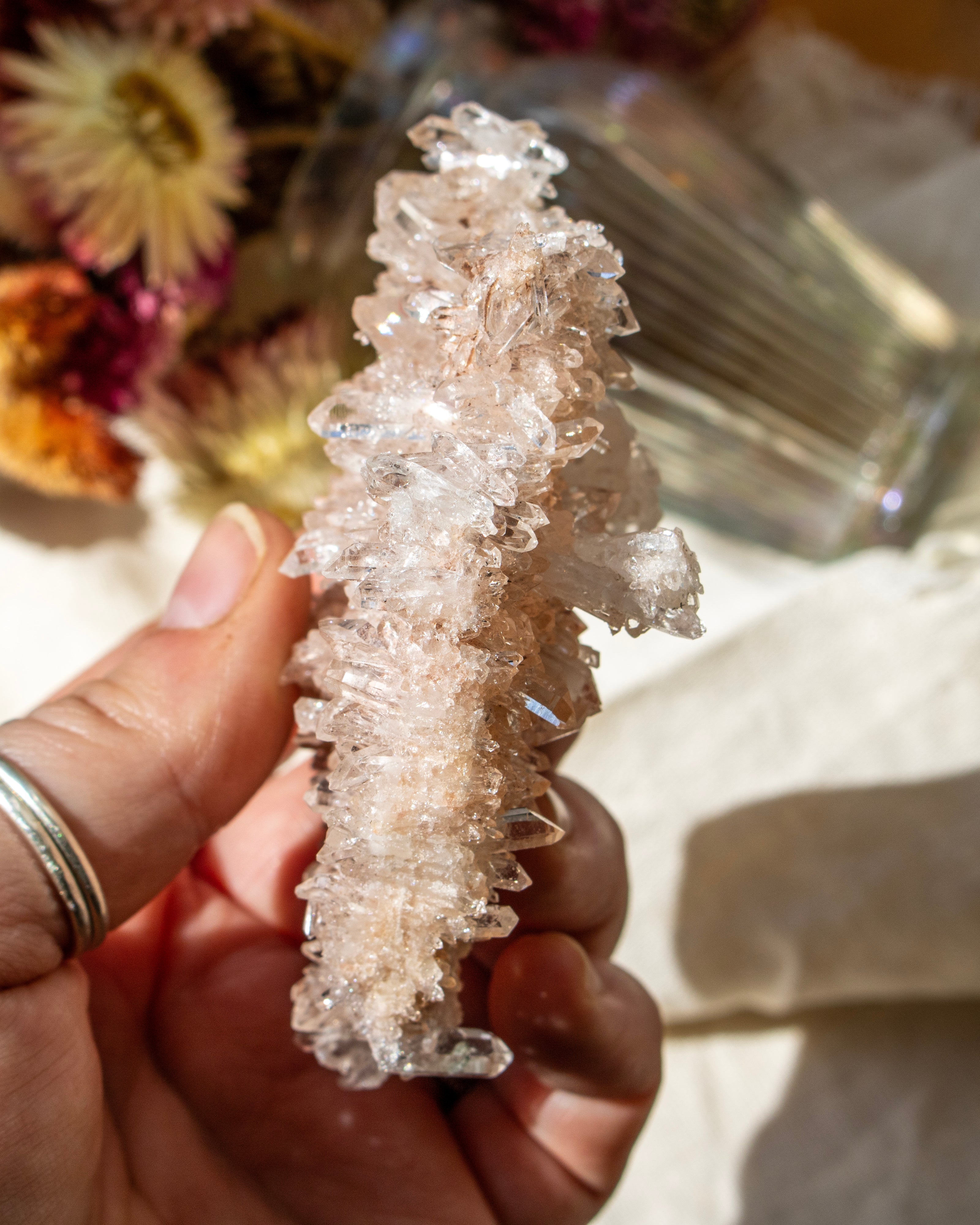 Clear crystal formation held by a hand with a blurred background