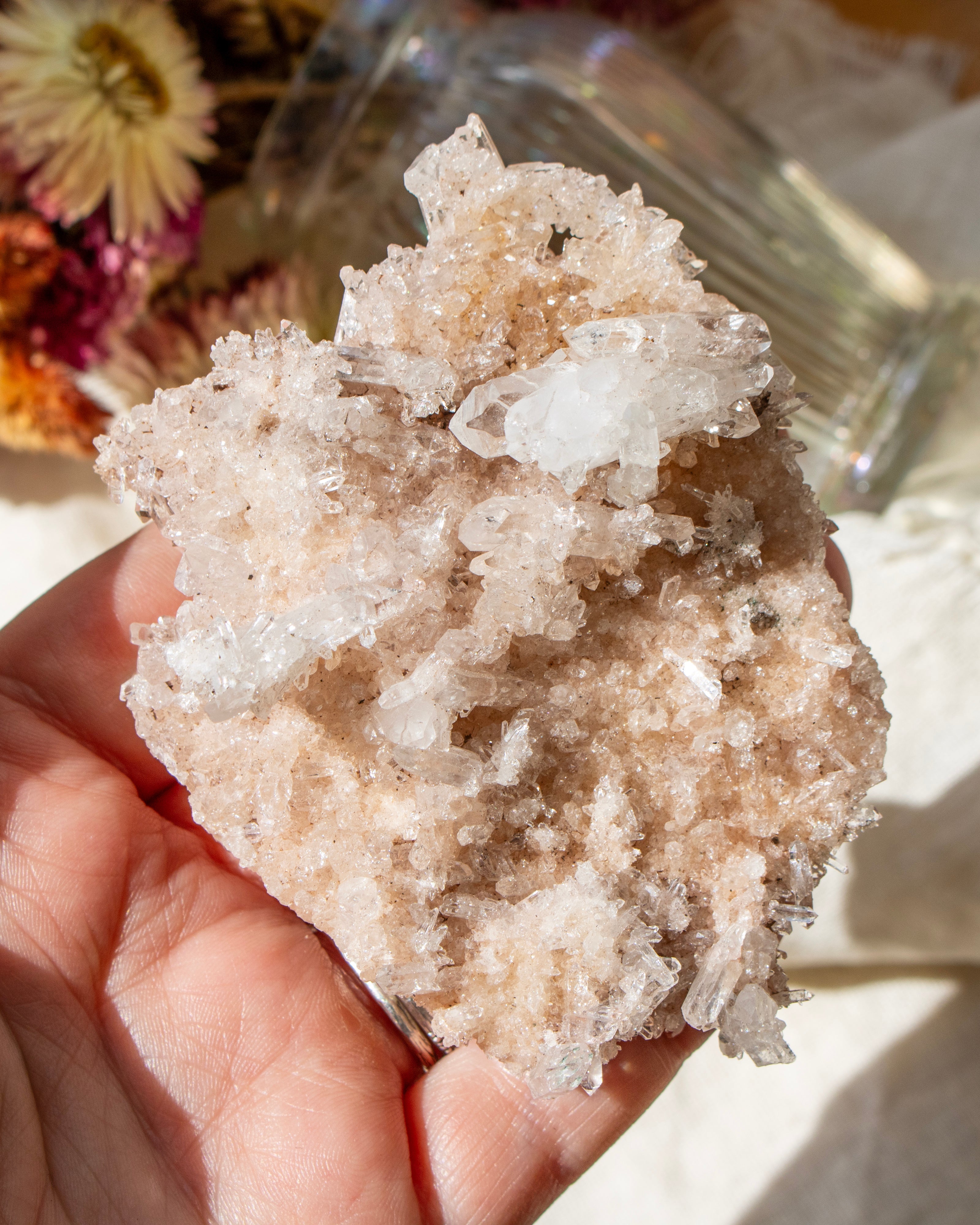 Hand holding a large crystal cluster against a neutral background