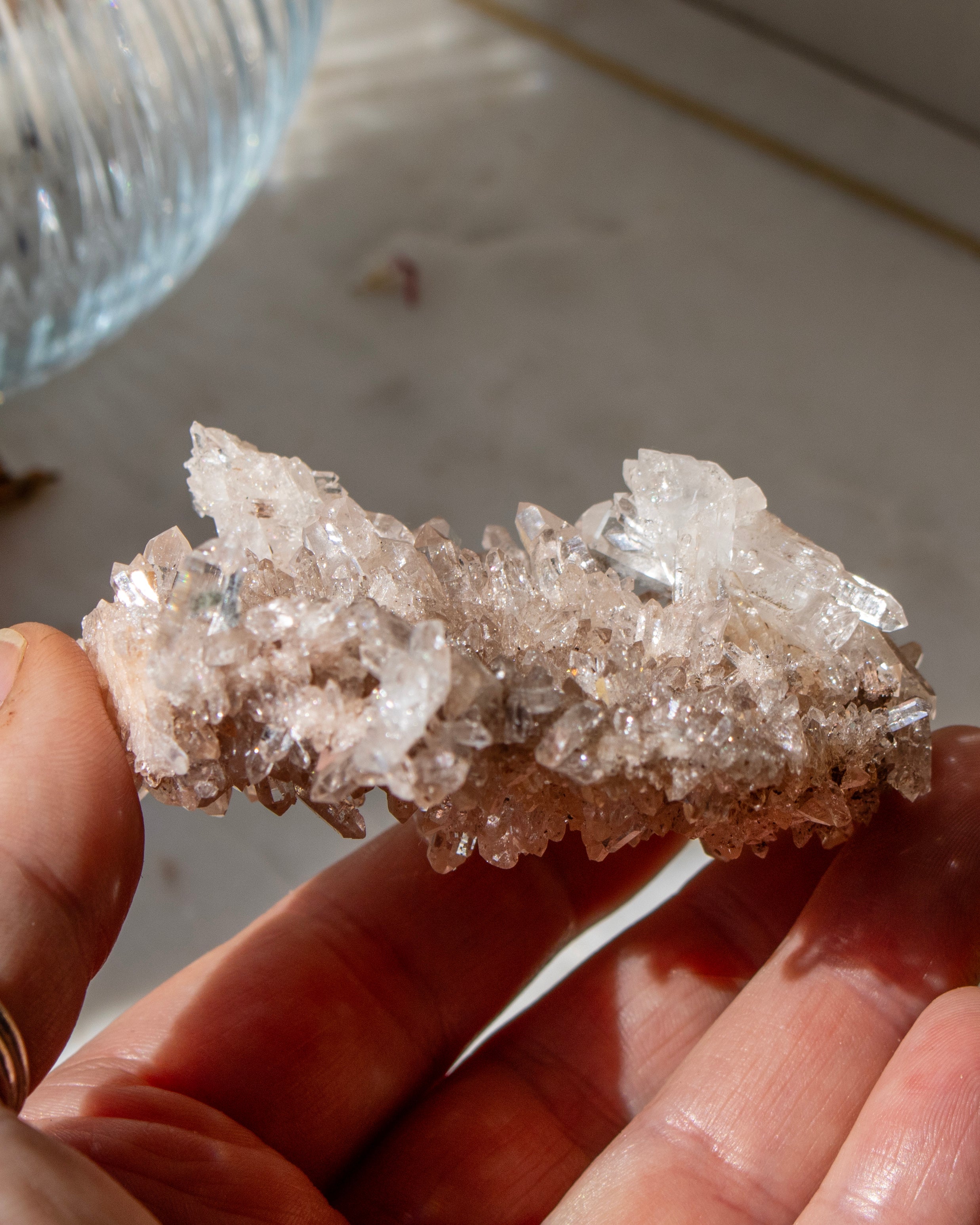 Hand holding a large crystal cluster against a neutral background