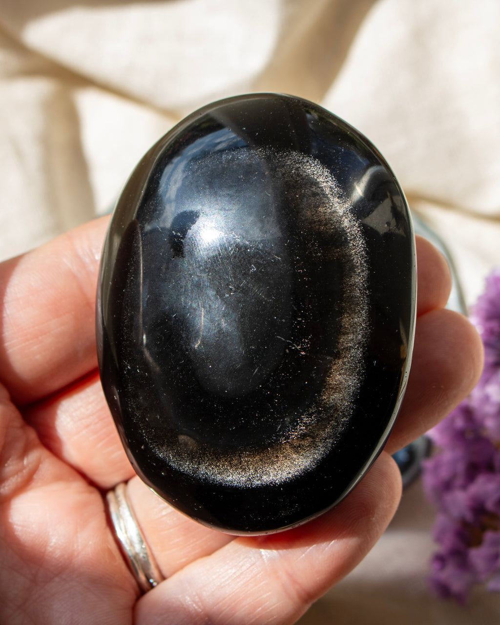 Black stone held in a hand with a blurred background