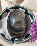 a black stone with a sliver sheen in a decorative ceramic bowl