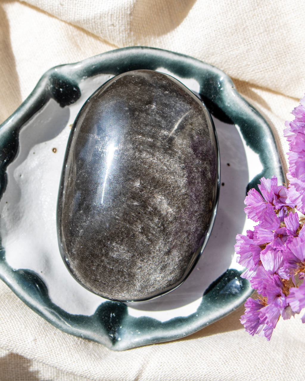 a black stone with a sliver sheen in a decorative ceramic bowl