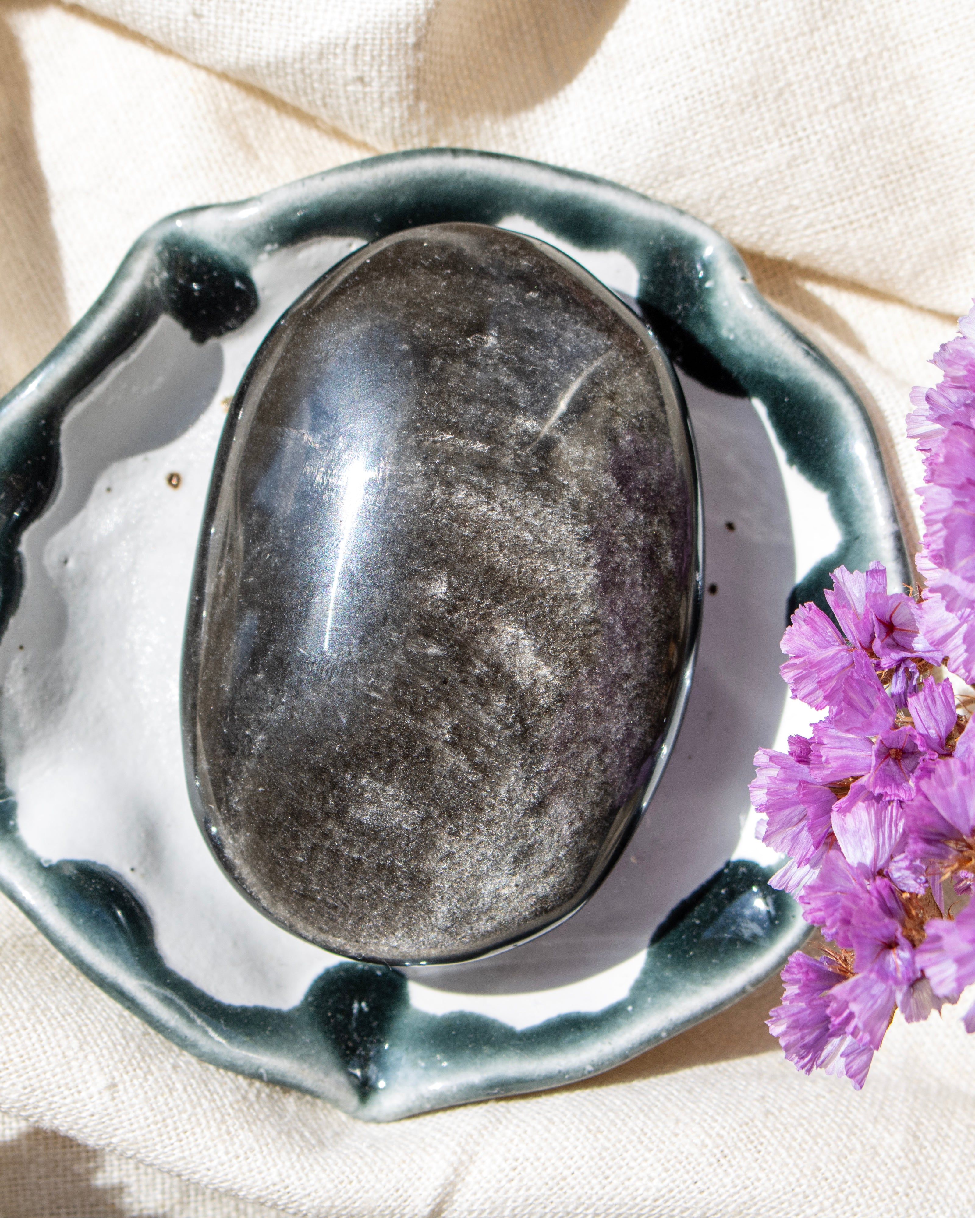 a black stone with a sliver sheen in a decorative ceramic bowl
