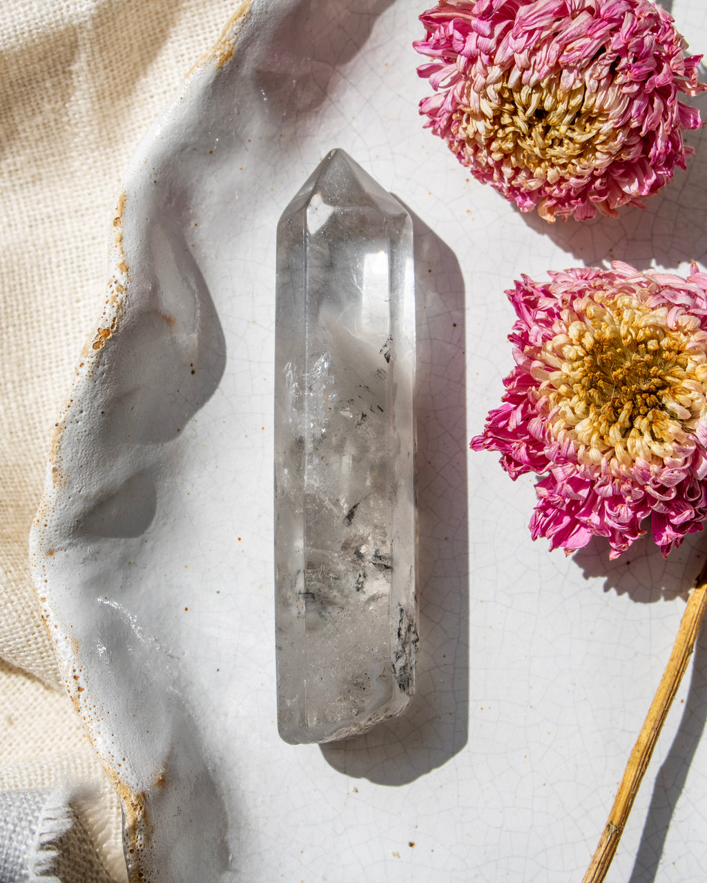 a clear crystal on a white ceramic plate with dried flowers