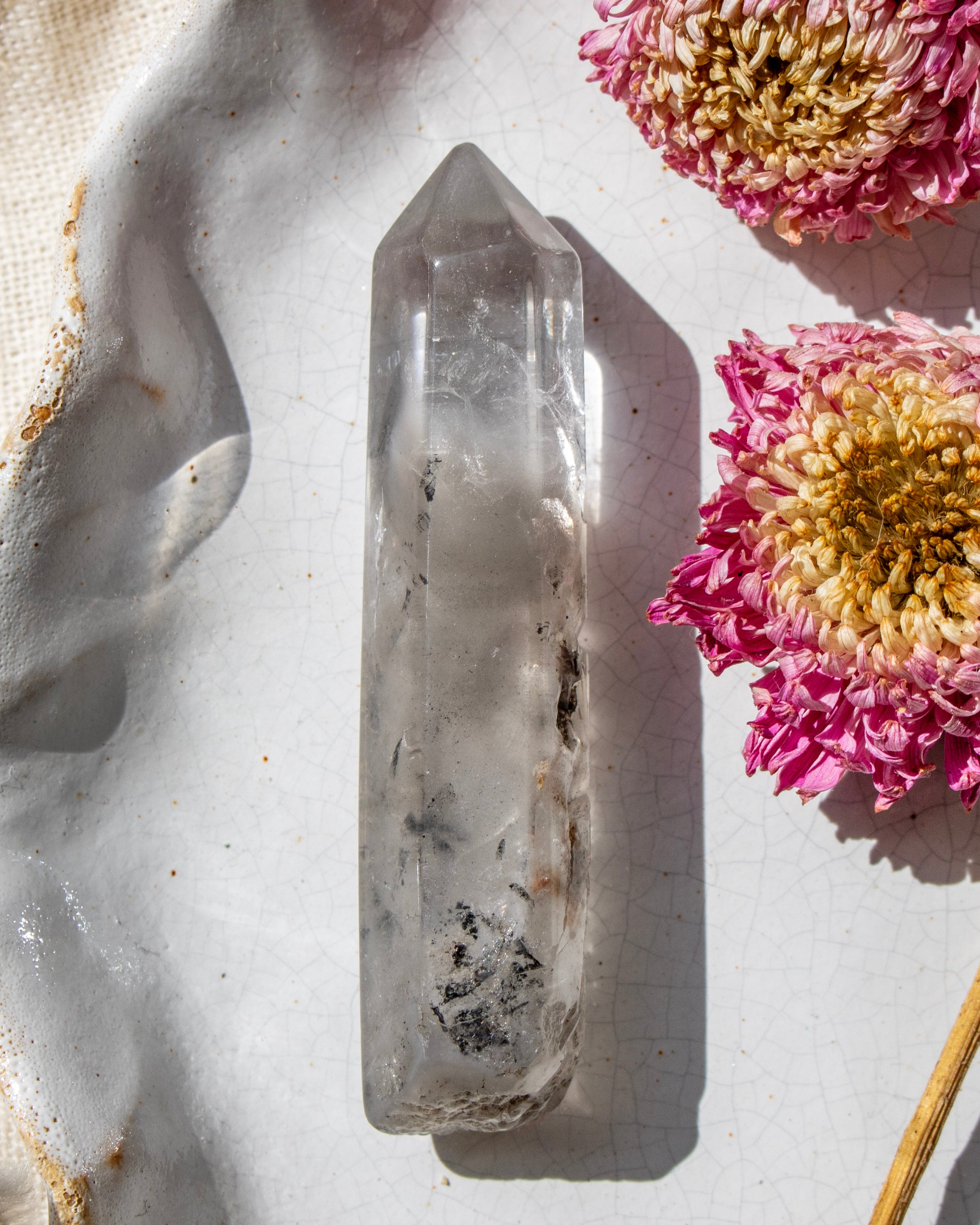 a clear crystal on a white ceramic plate with dried flowers