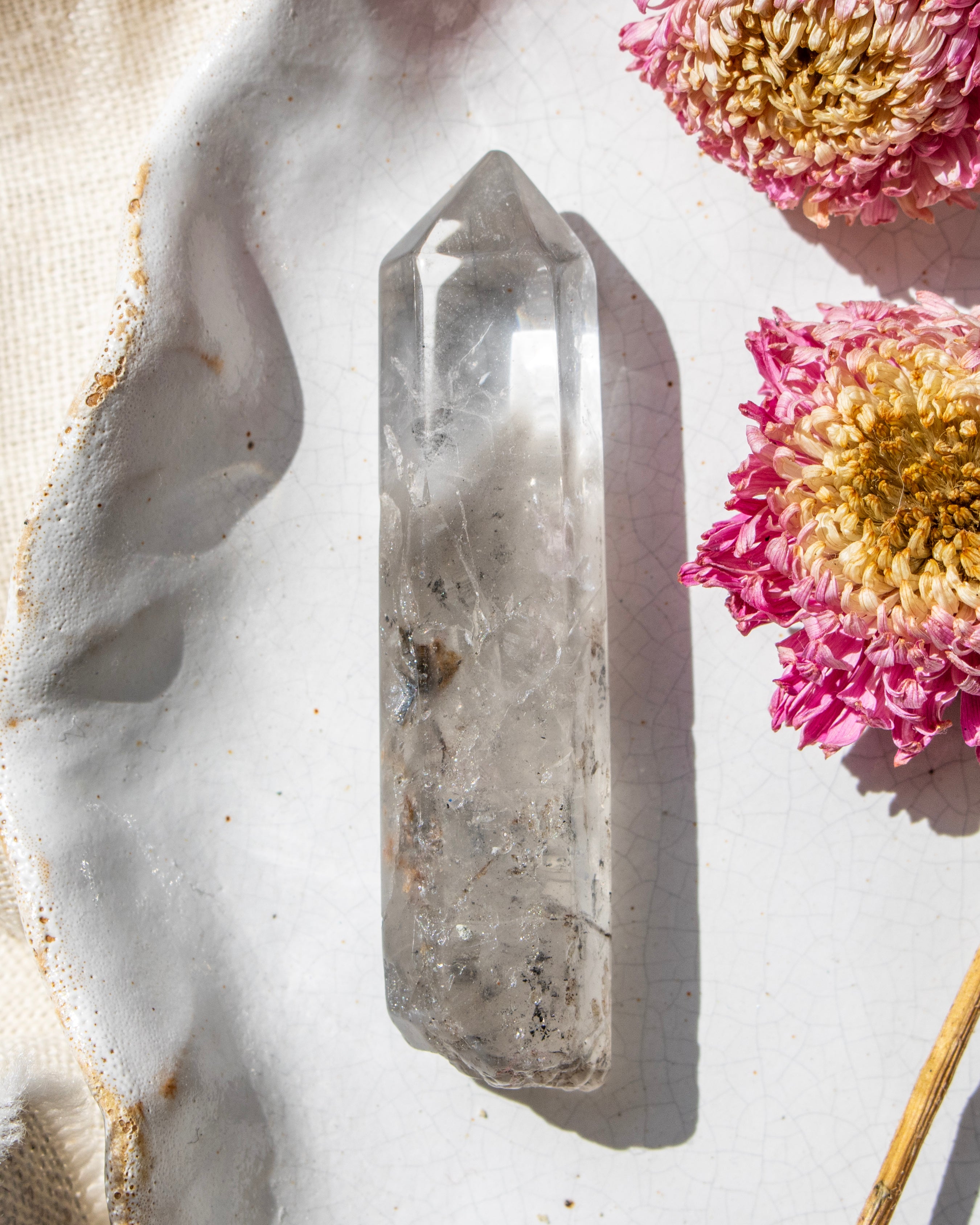 a clear crystal on a white ceramic plate with dried flowers