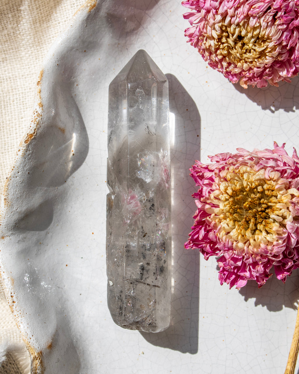 a clear crystal on a white ceramic plate with dried flowers