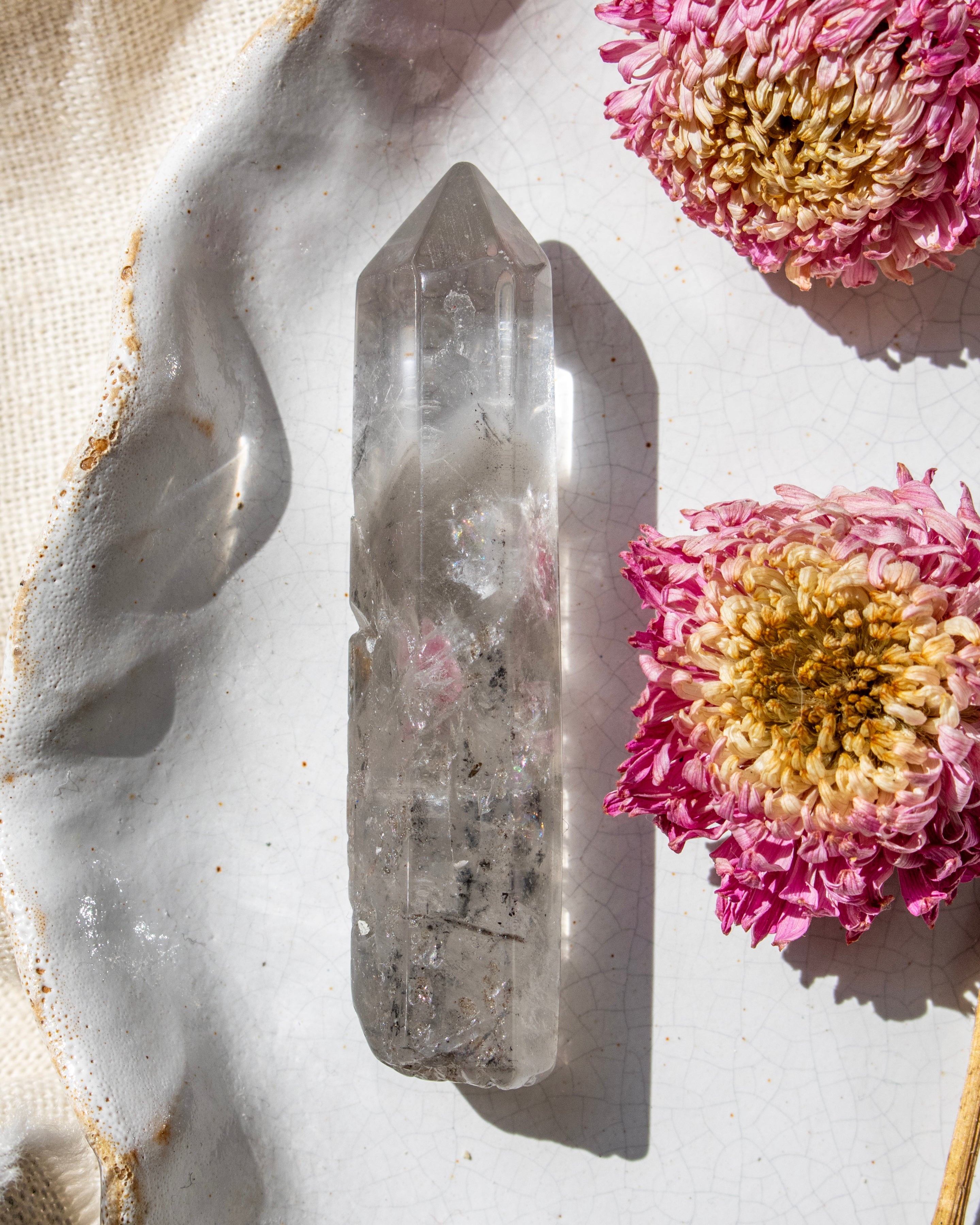 a clear crystal on a white ceramic plate with dried flowers