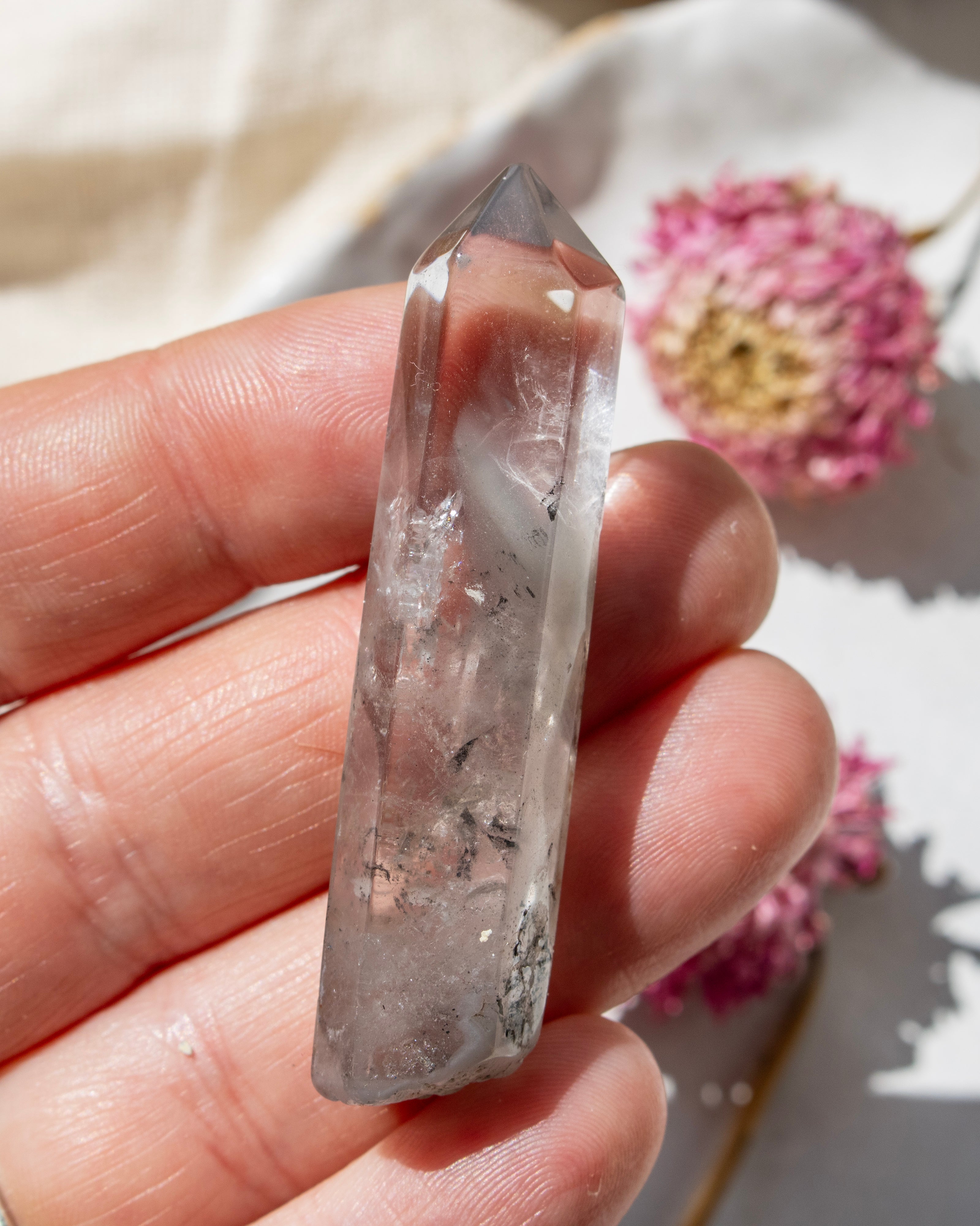 a clear crystal being held with dried flowers
