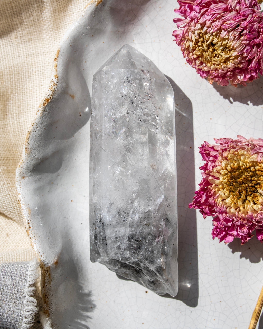 a clear crystal on a white ceramic plate with dried flowers