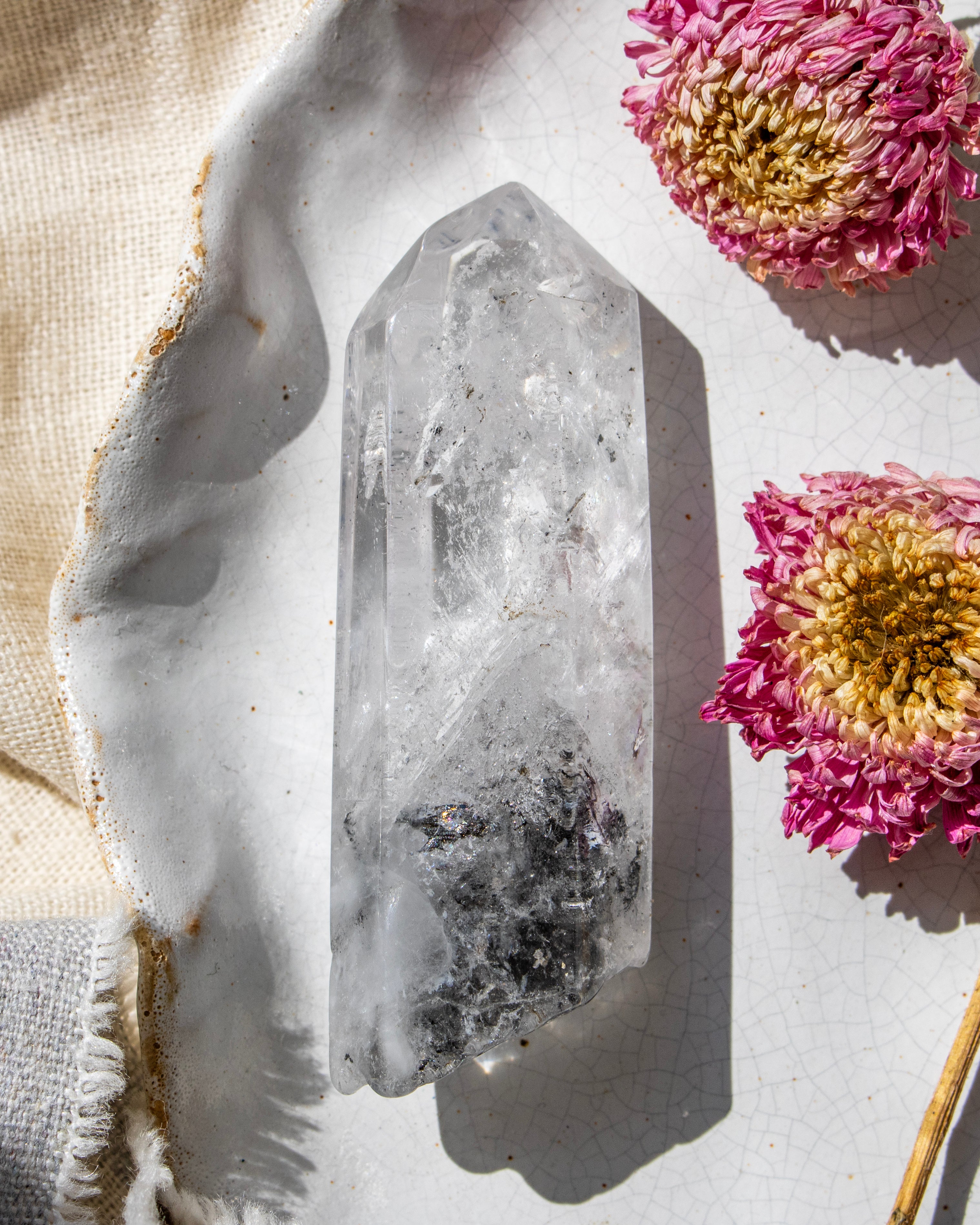a clear crystal on a white ceramic plate with dried flowers
