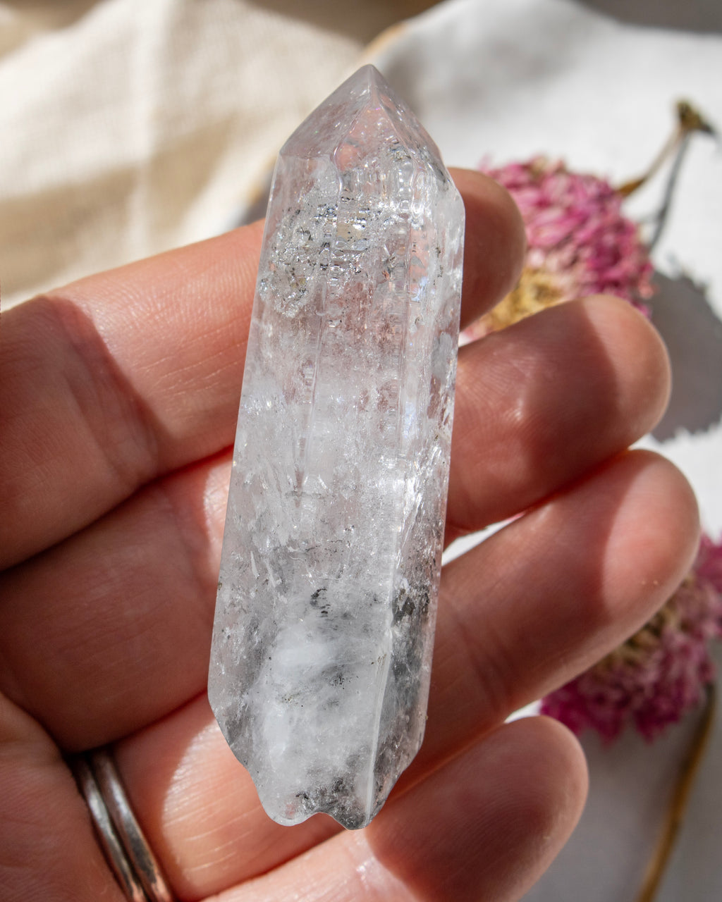 a clear crystal being held with dried flowers