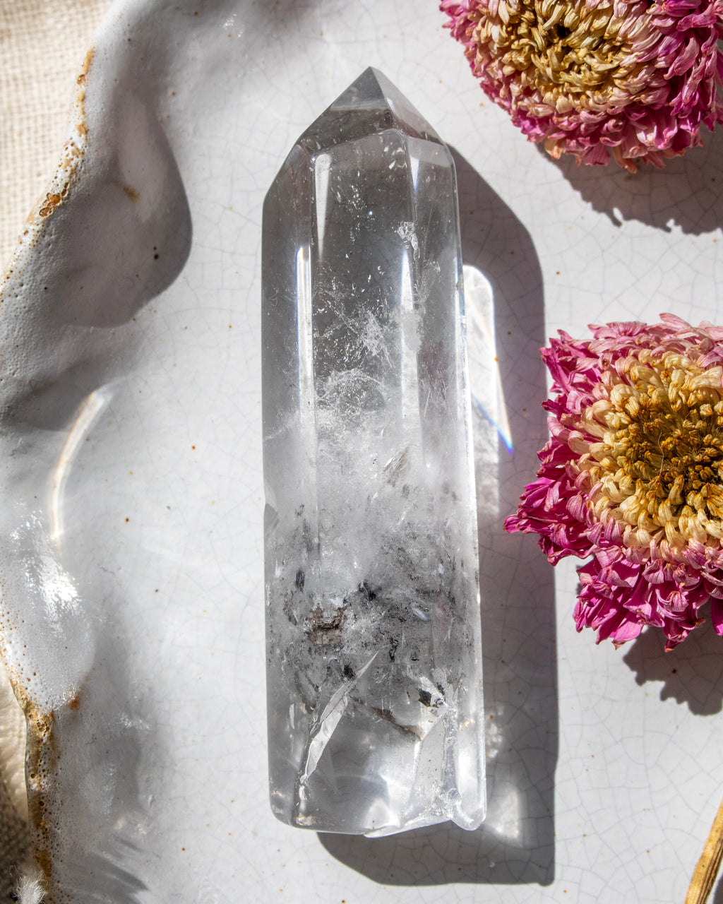 a clear crystal on a white ceramic plate with dried flowers