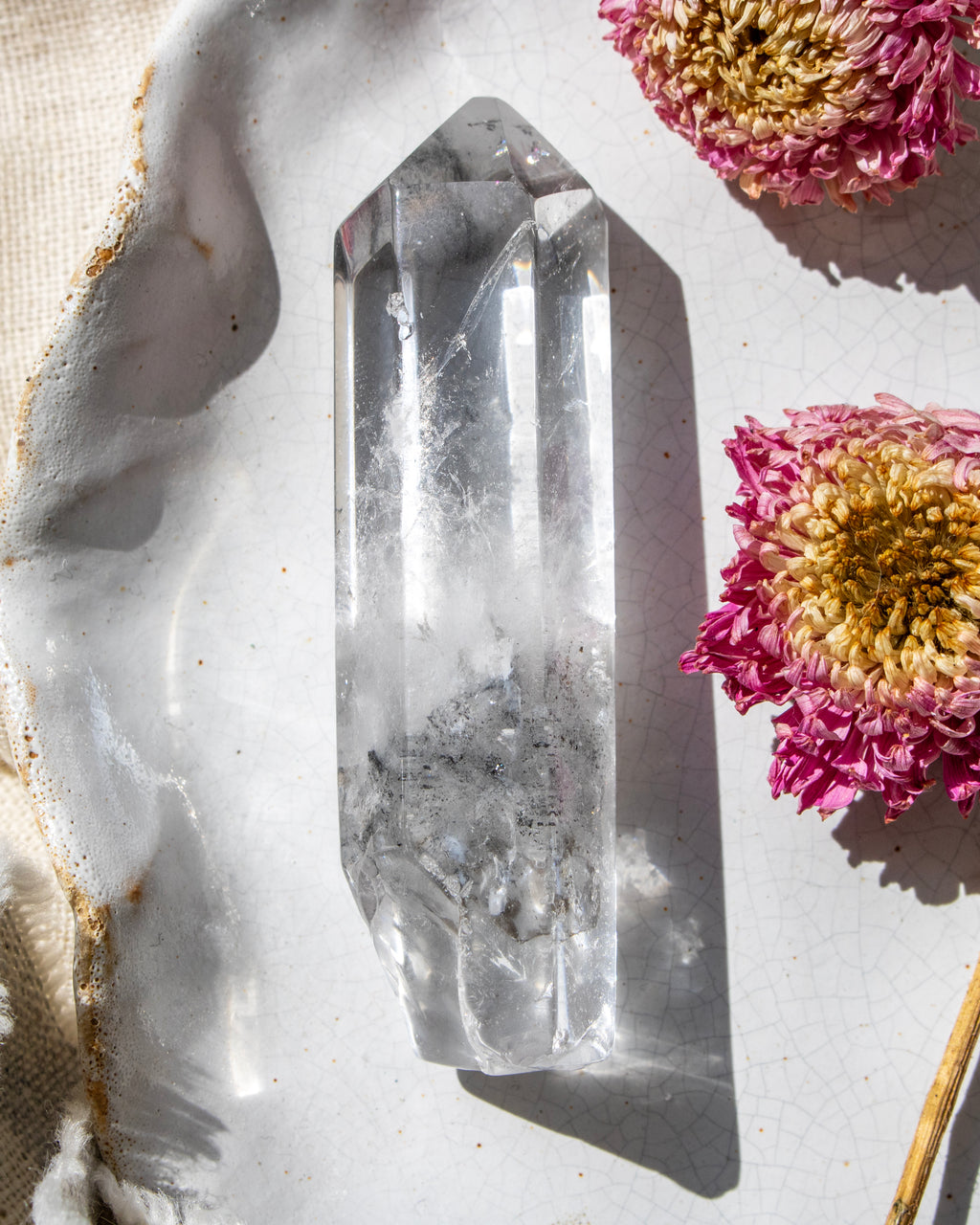 a clear crystal on a white ceramic plate with dried flowers