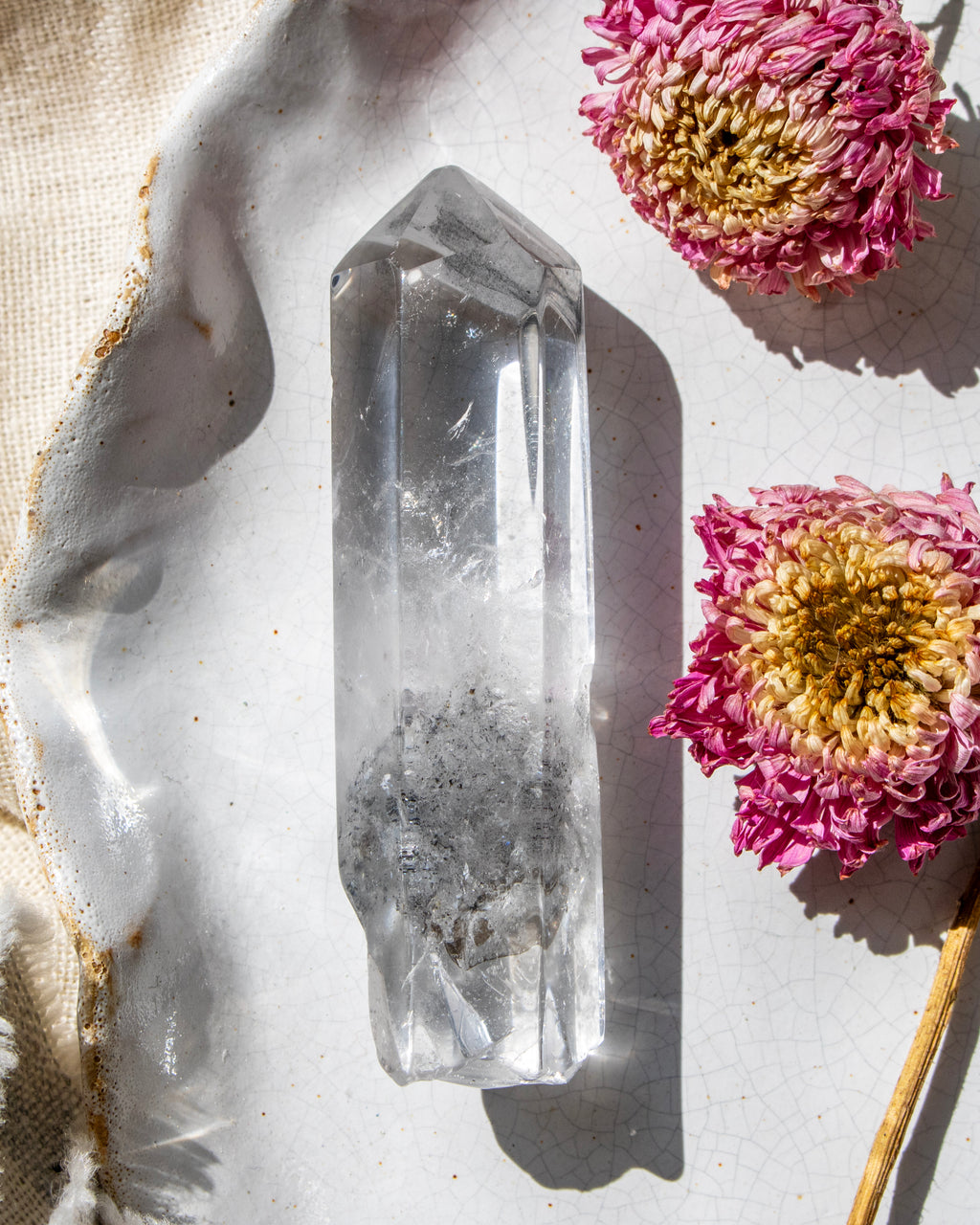 a clear crystal on a white ceramic plate with dried flowers