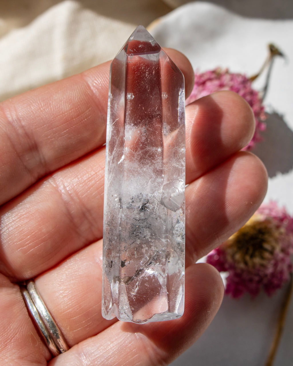 Clear crystal held in a hand with a blurred natural background