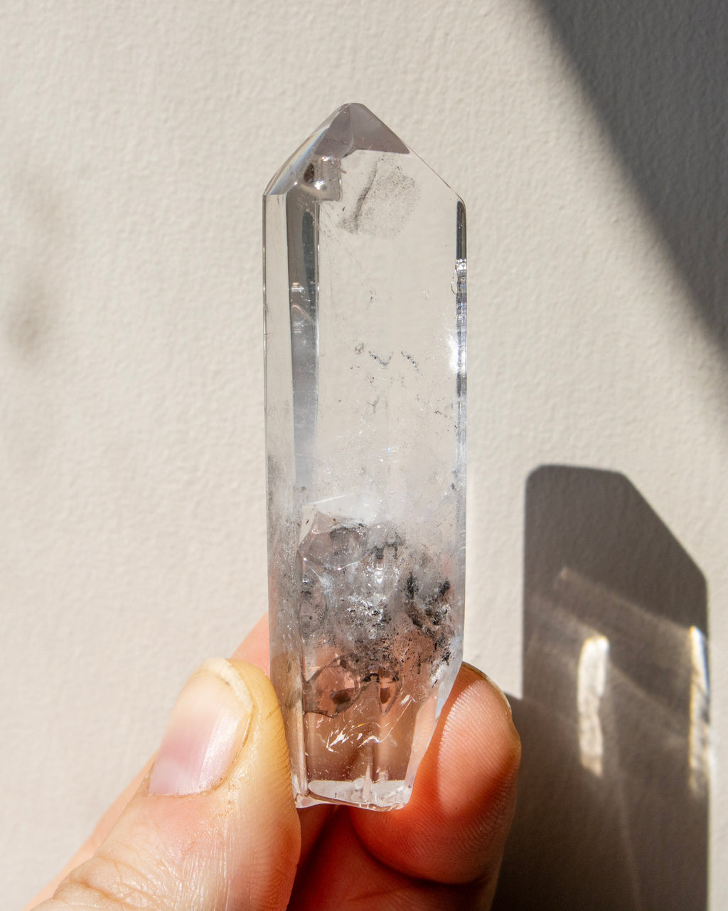 a clear crystal being held with a neutral background
