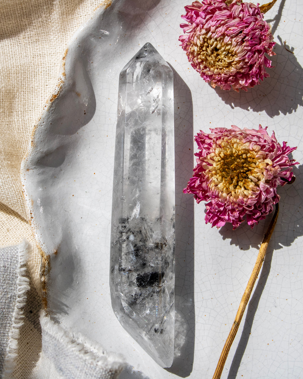 a clear crystal on a white ceramic plate with dried flowers