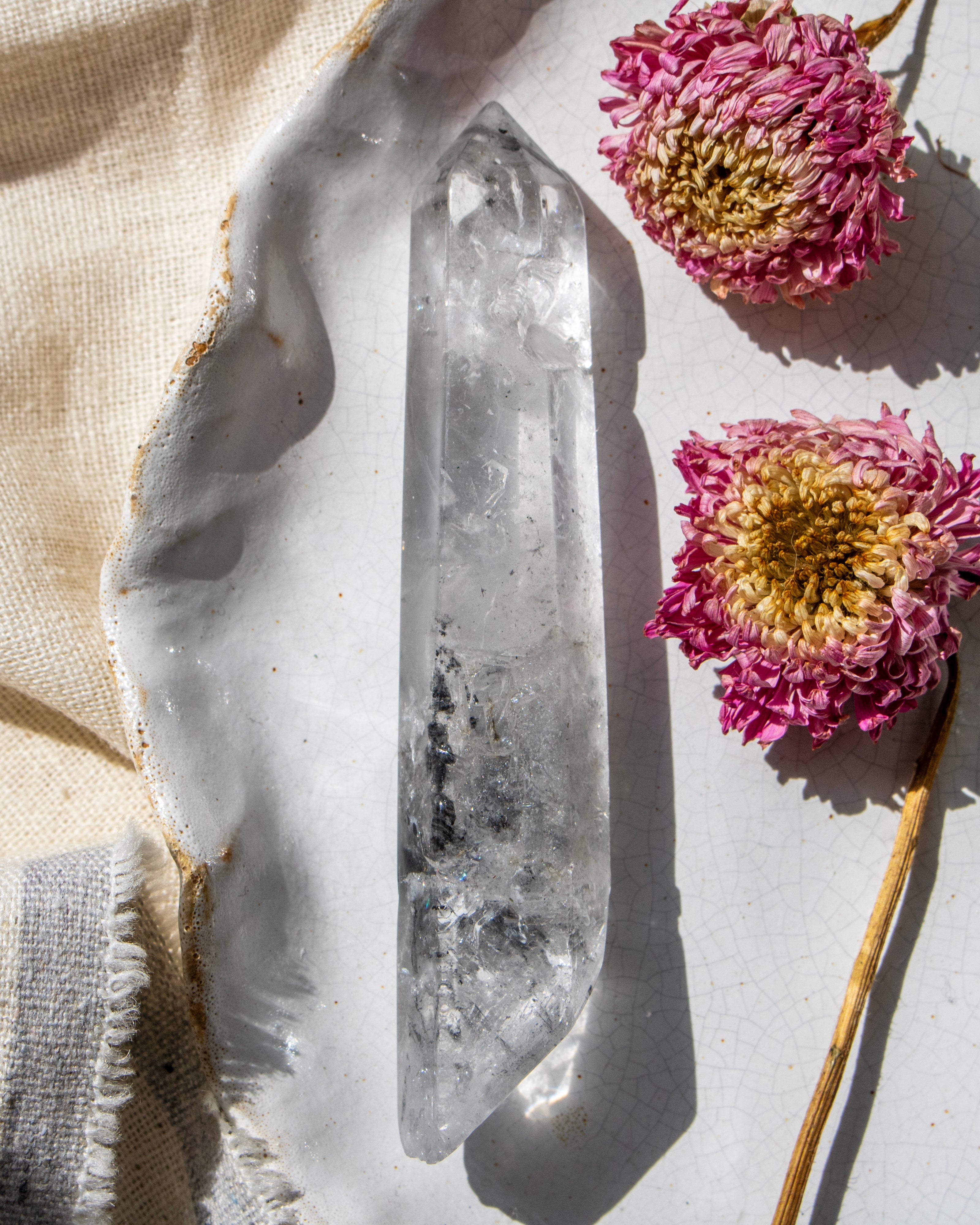 a clear crystal on a white ceramic plate with dried flowers