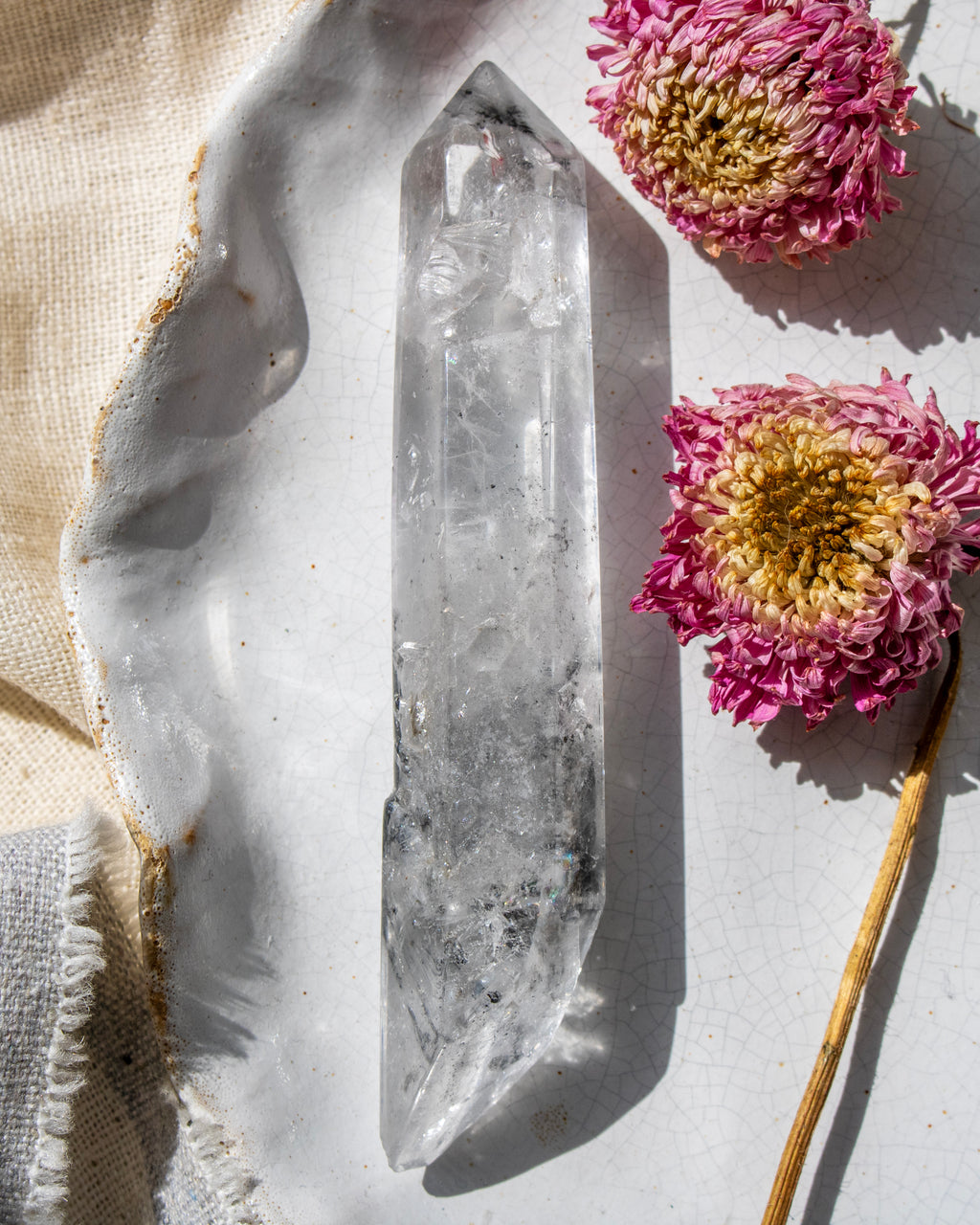 Clear crystal point on a textured surface with pink flowers
