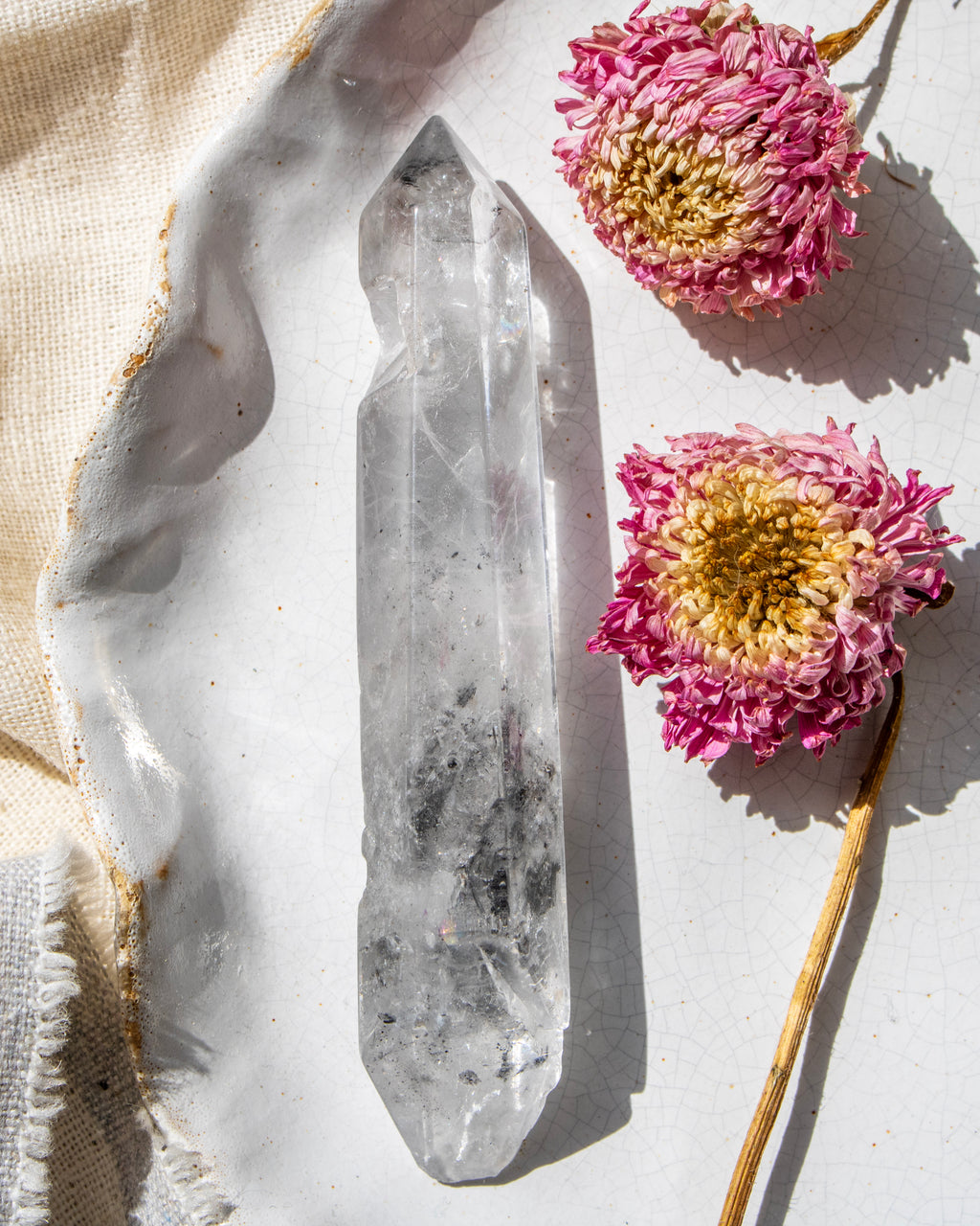 Crystal point with pink flowers on a light background