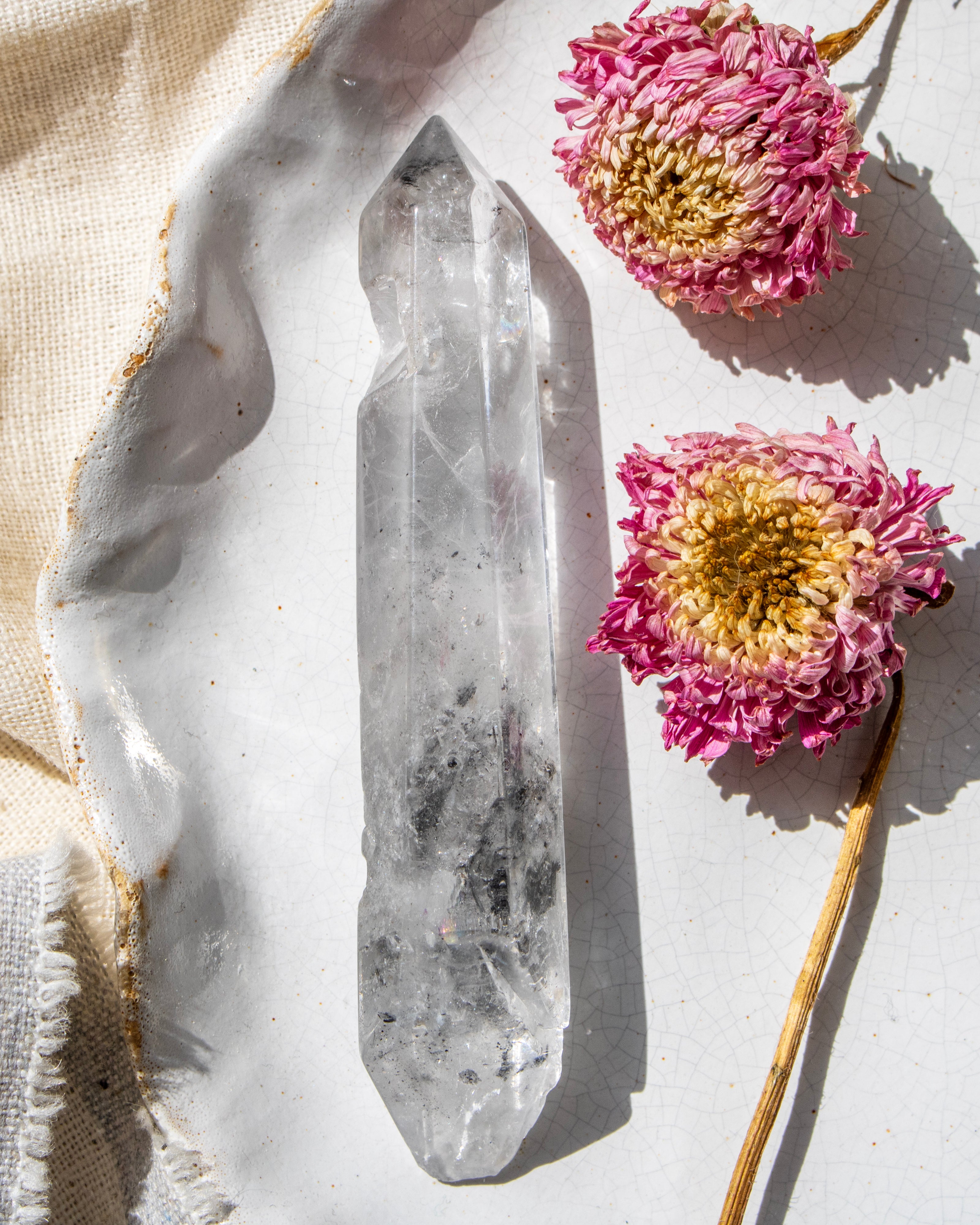 Crystal point with pink flowers on a light background