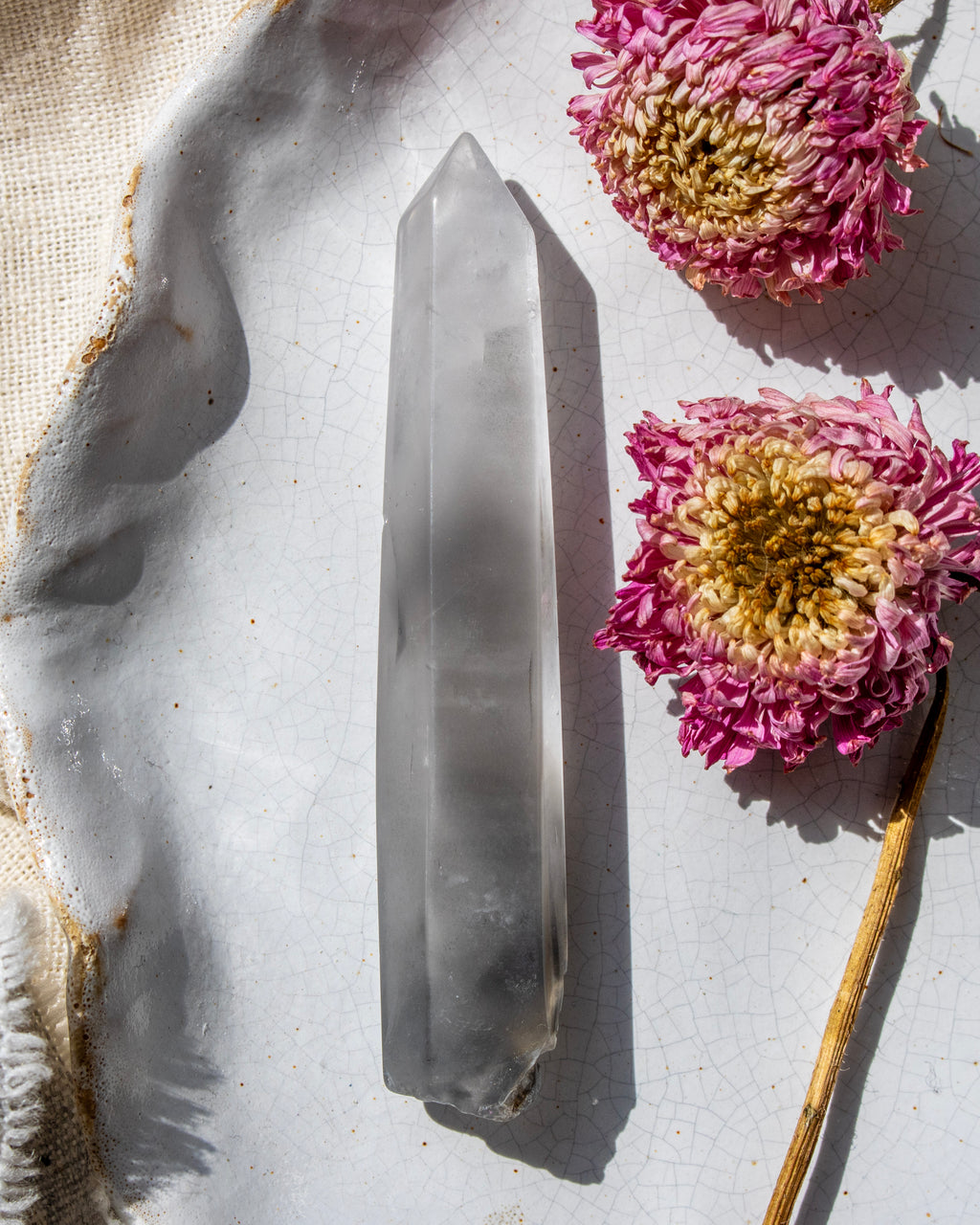 a clear crystal on a white ceramic plate with dried flowers
