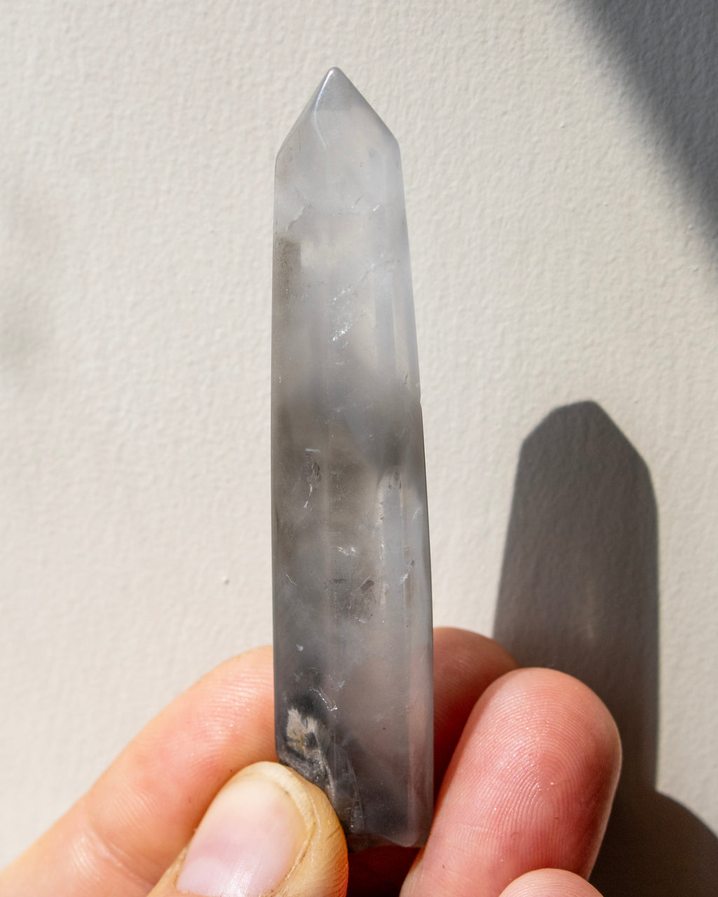 a clear quartz crystal being held with a neutral background