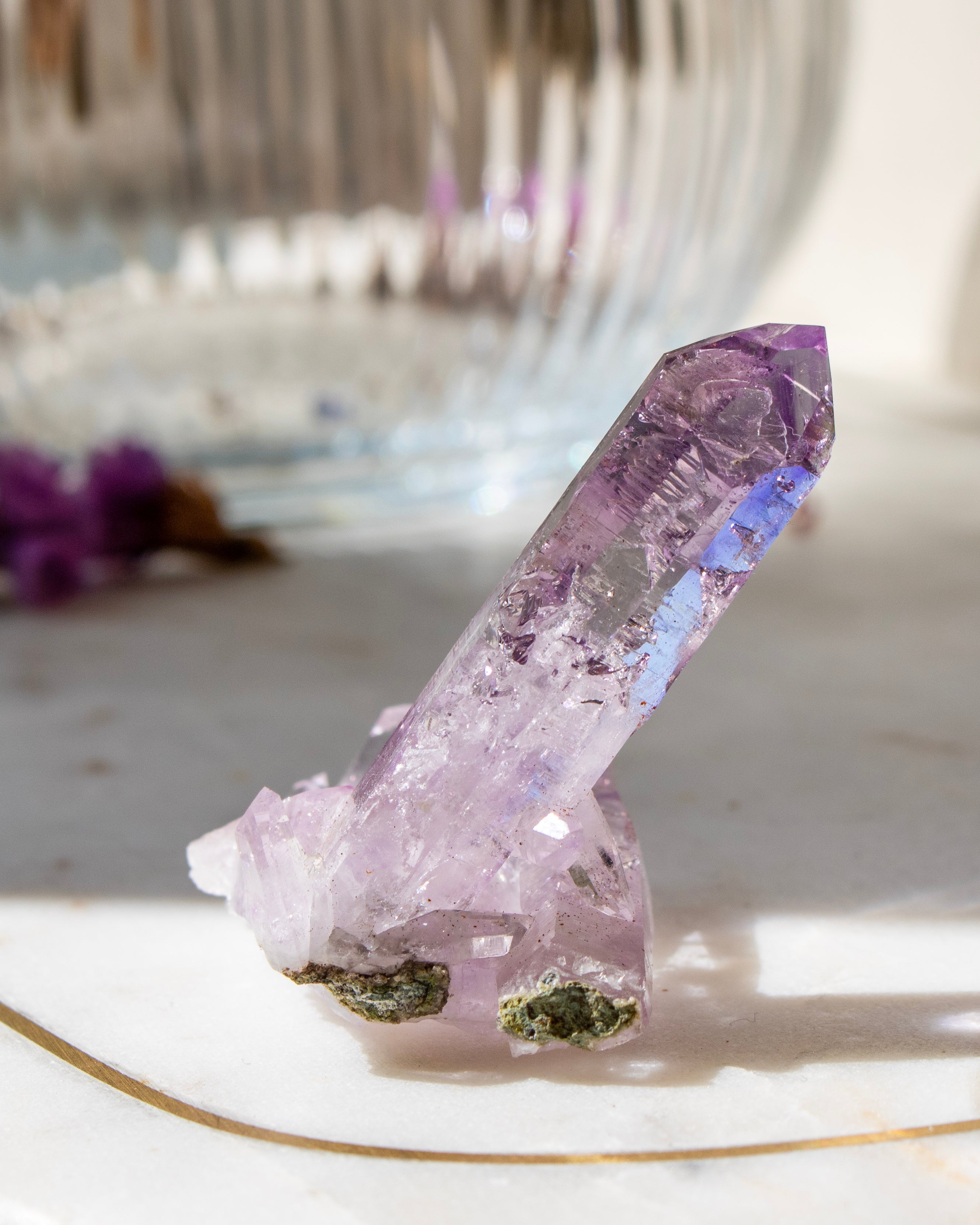 Amethyst crystal on a marble surface with a blurred background