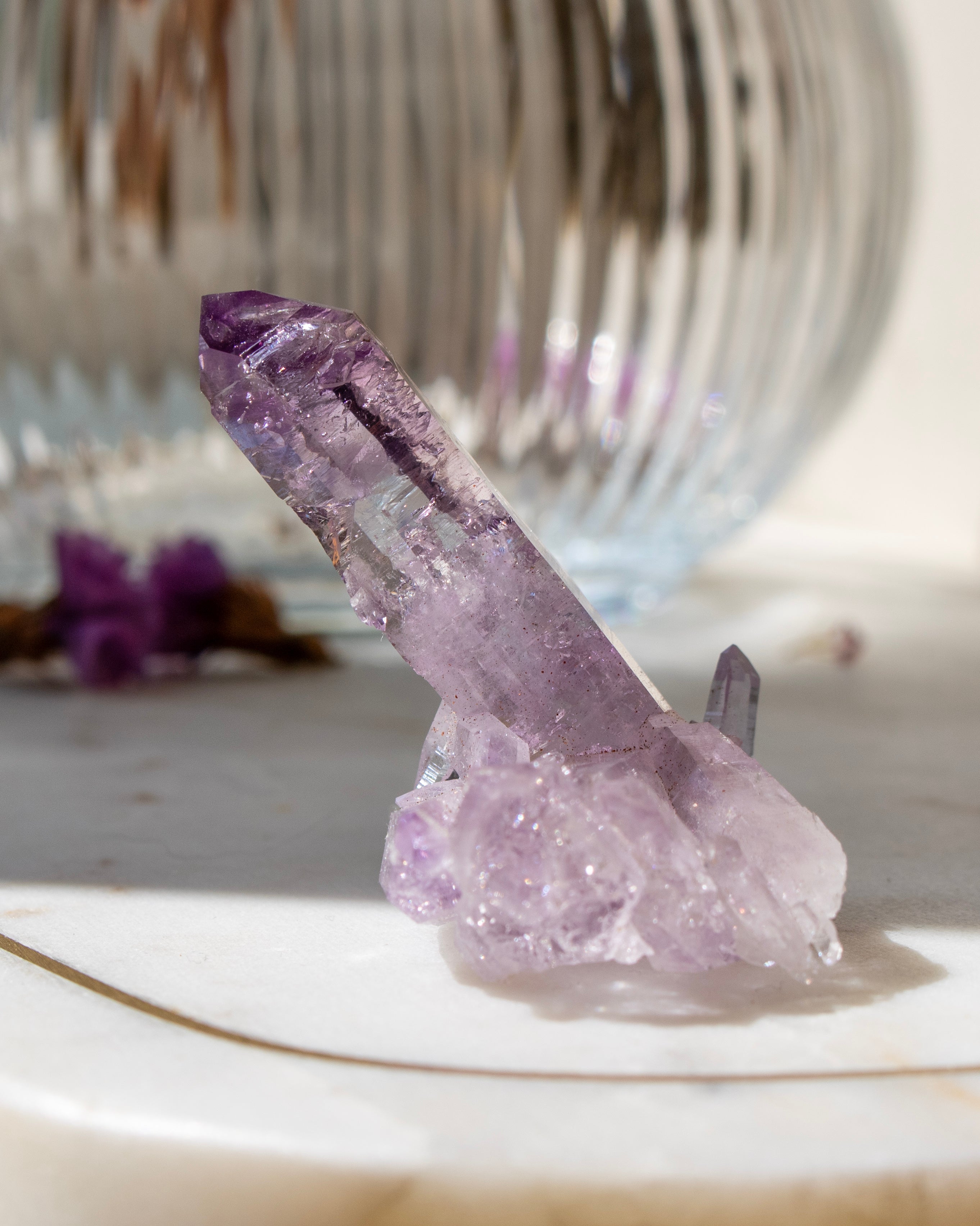 Amethyst crystal on a white surface with a blurred background