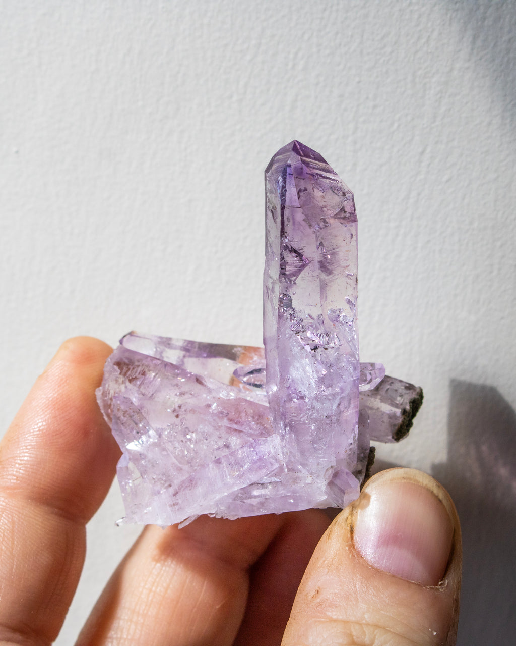 Hand holding a purple crystal against a white background