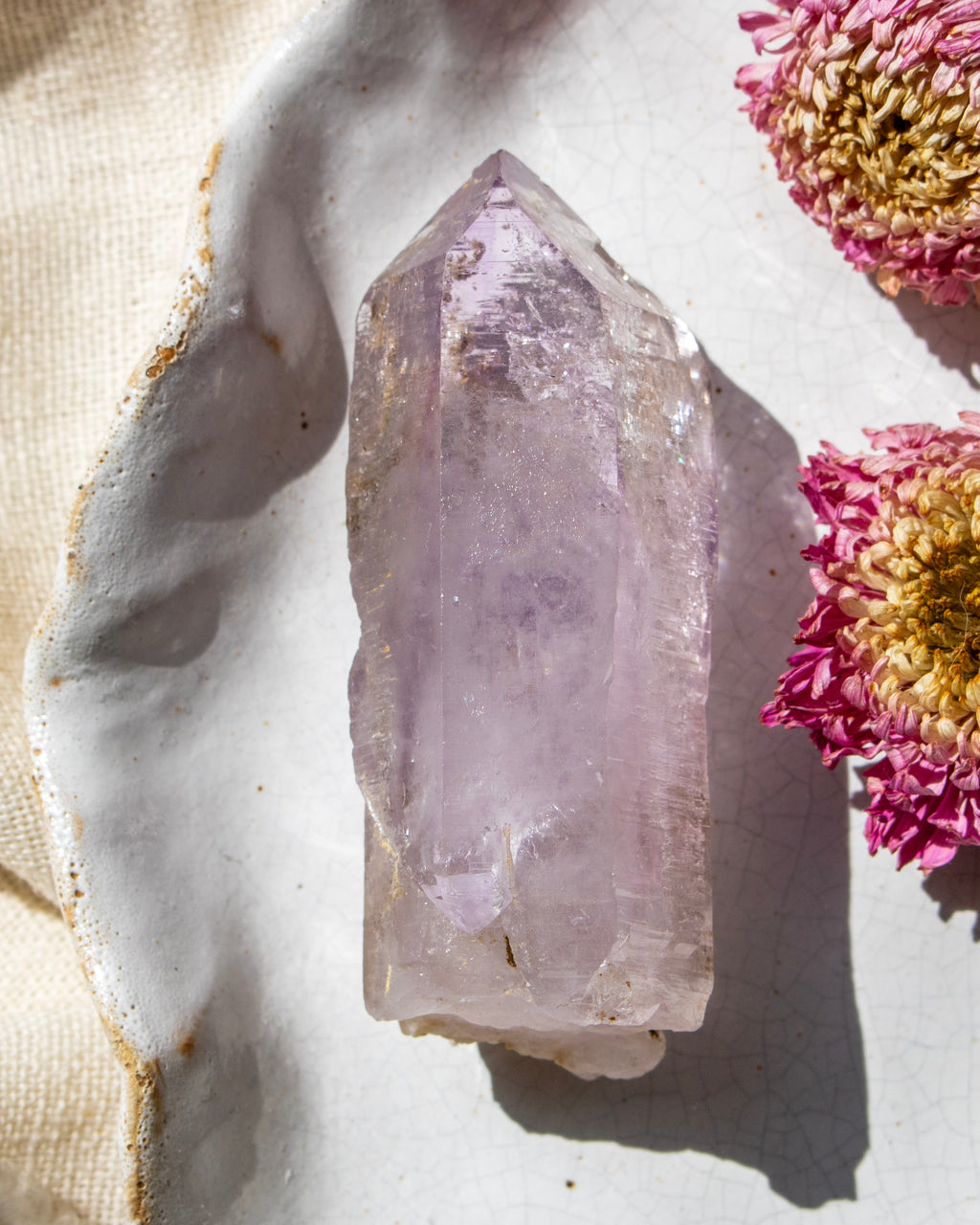 Amethyst crystal on a marble surface with pink flowers
