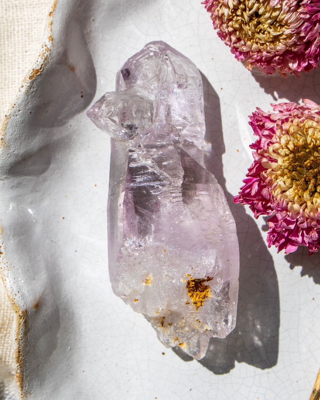 Clear crystal with gold inclusions on a light background with pink flowers