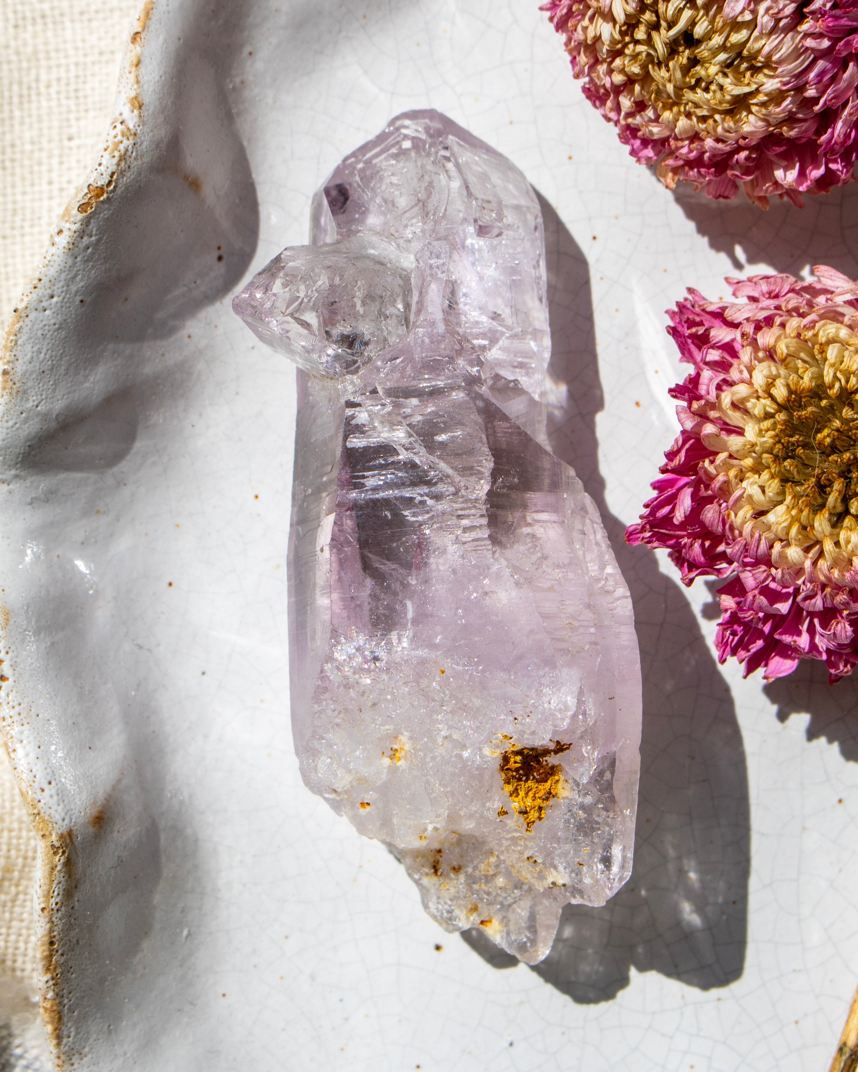 Clear crystal with gold inclusions on a light background with pink flowers