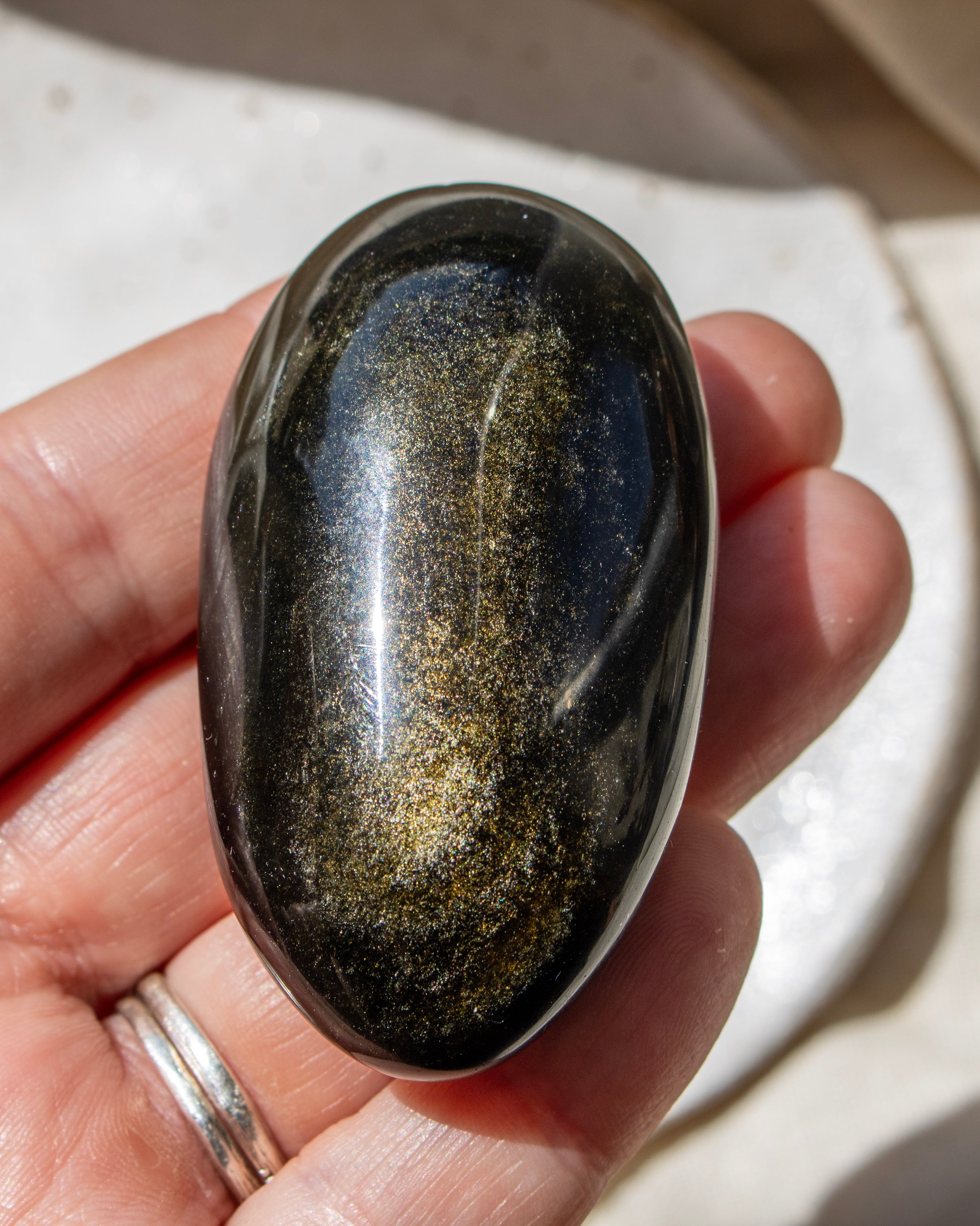 Oval-shaped stone held in a hand with a neutral background