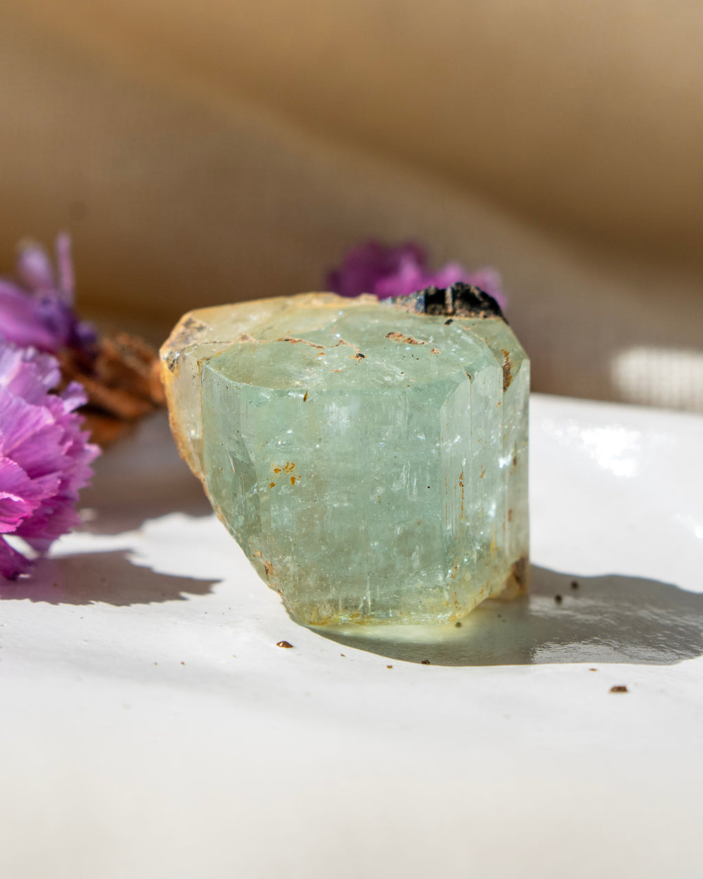 Crystal on a white surface with purple flowers