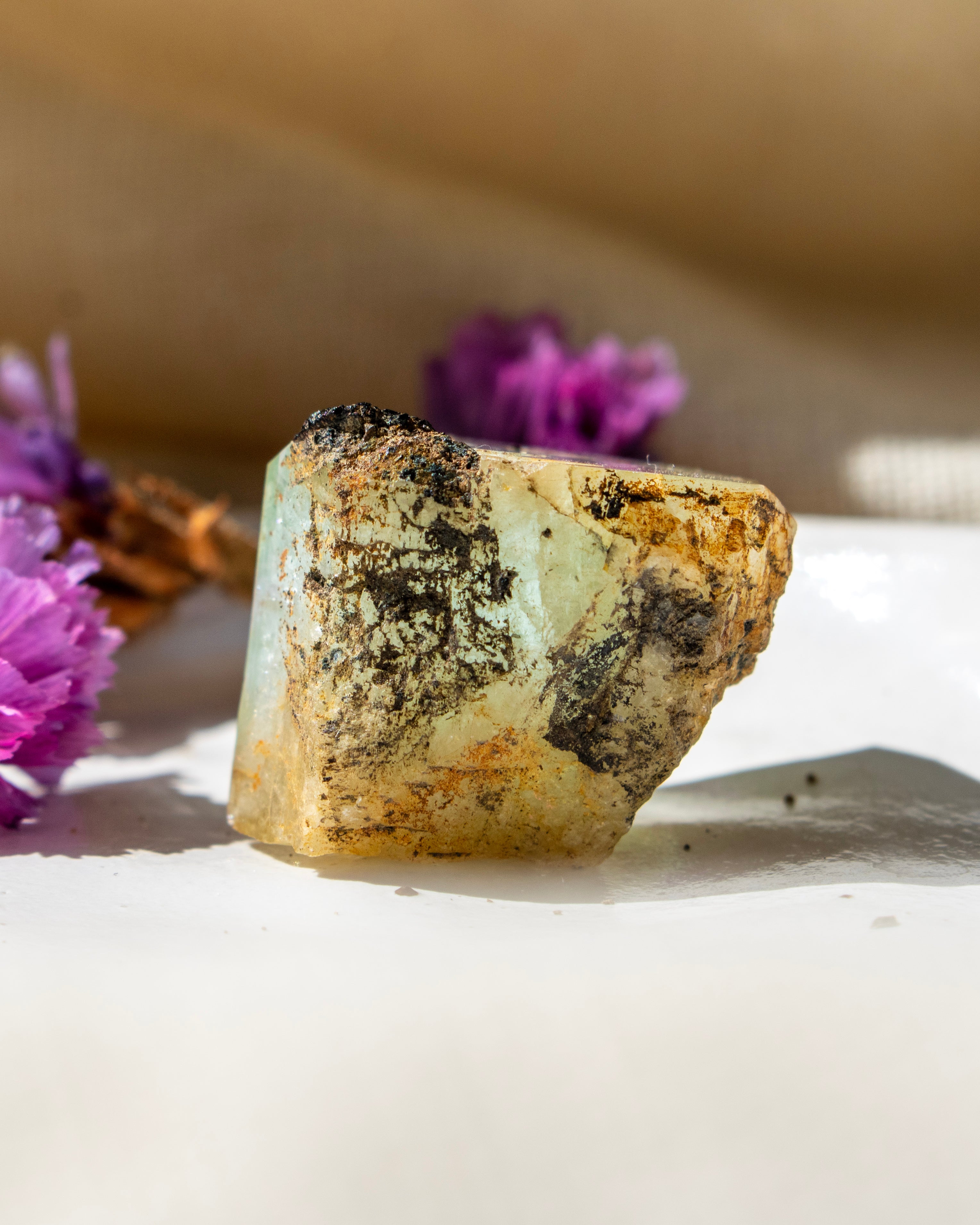 Mineral specimen with purple flowers on a neutral background