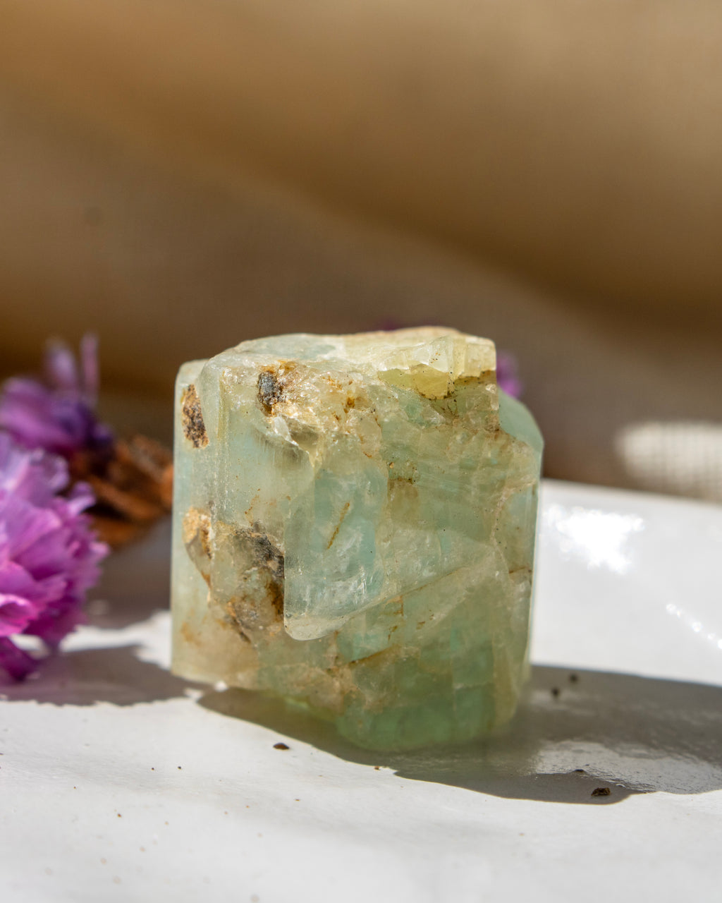 Crystal on a white surface with purple flowers in the background