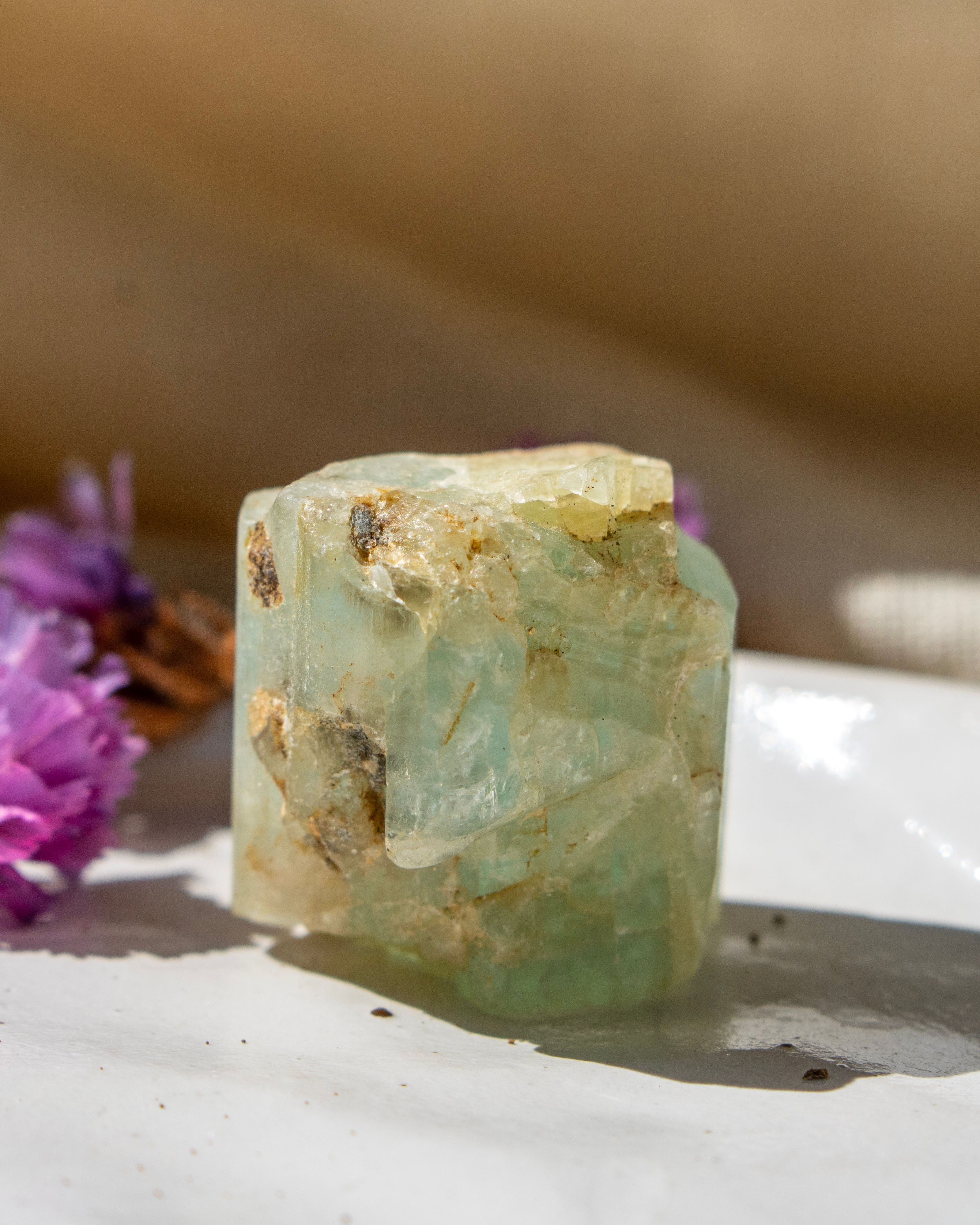 Crystal on a white surface with purple flowers in the background