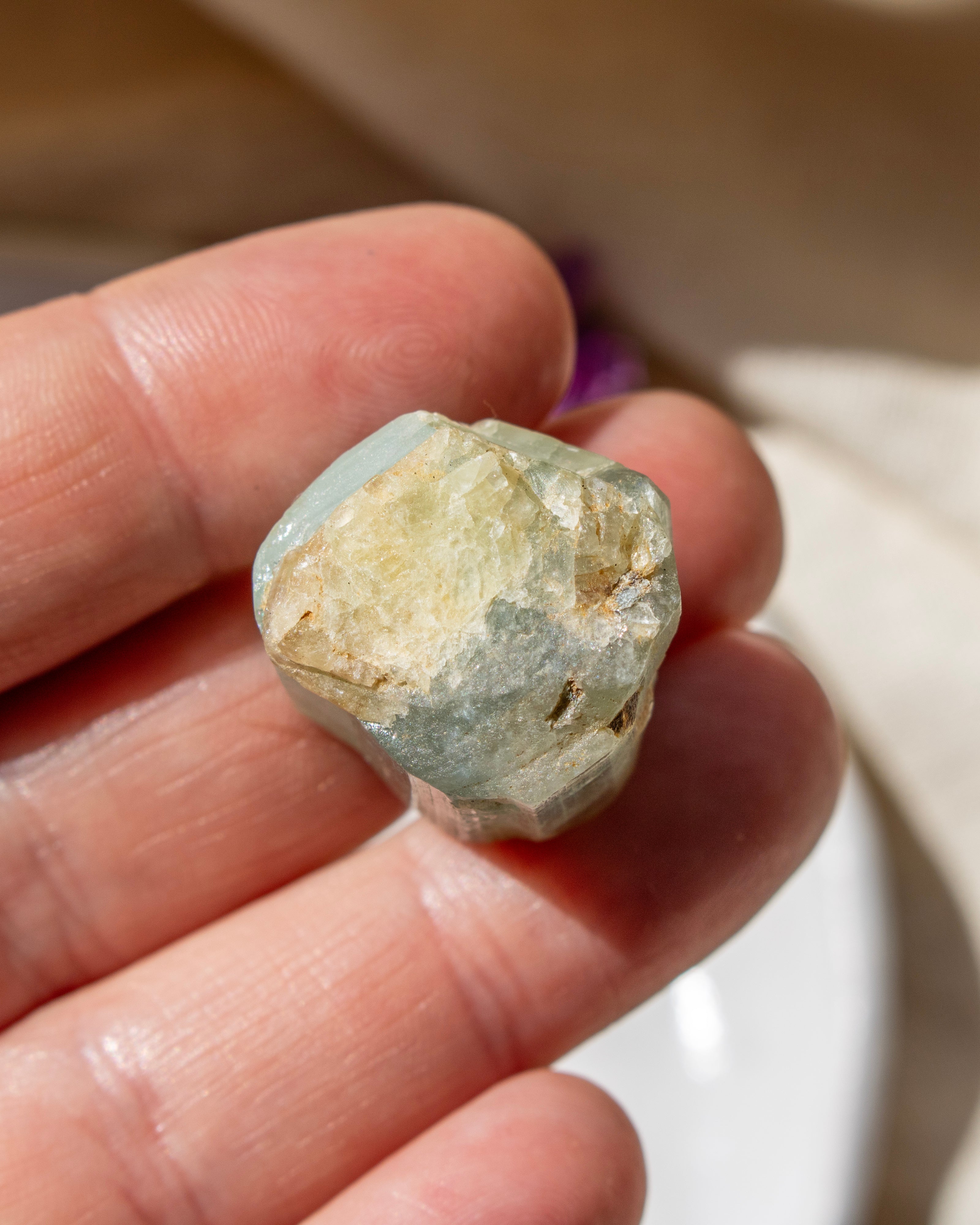 Hand holding a rough crystal rock against a blurred background