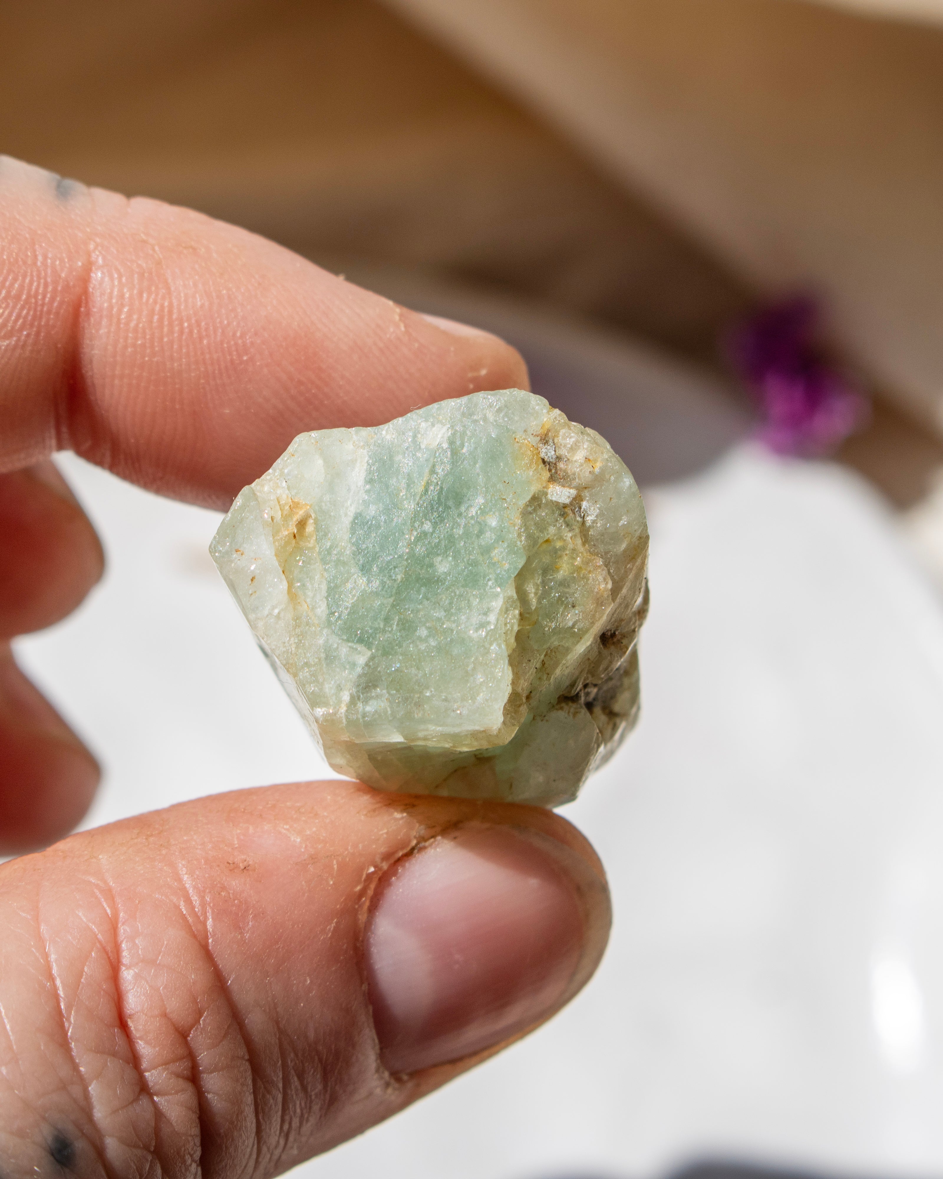 Hand holding a green crystal rock with a blurred background