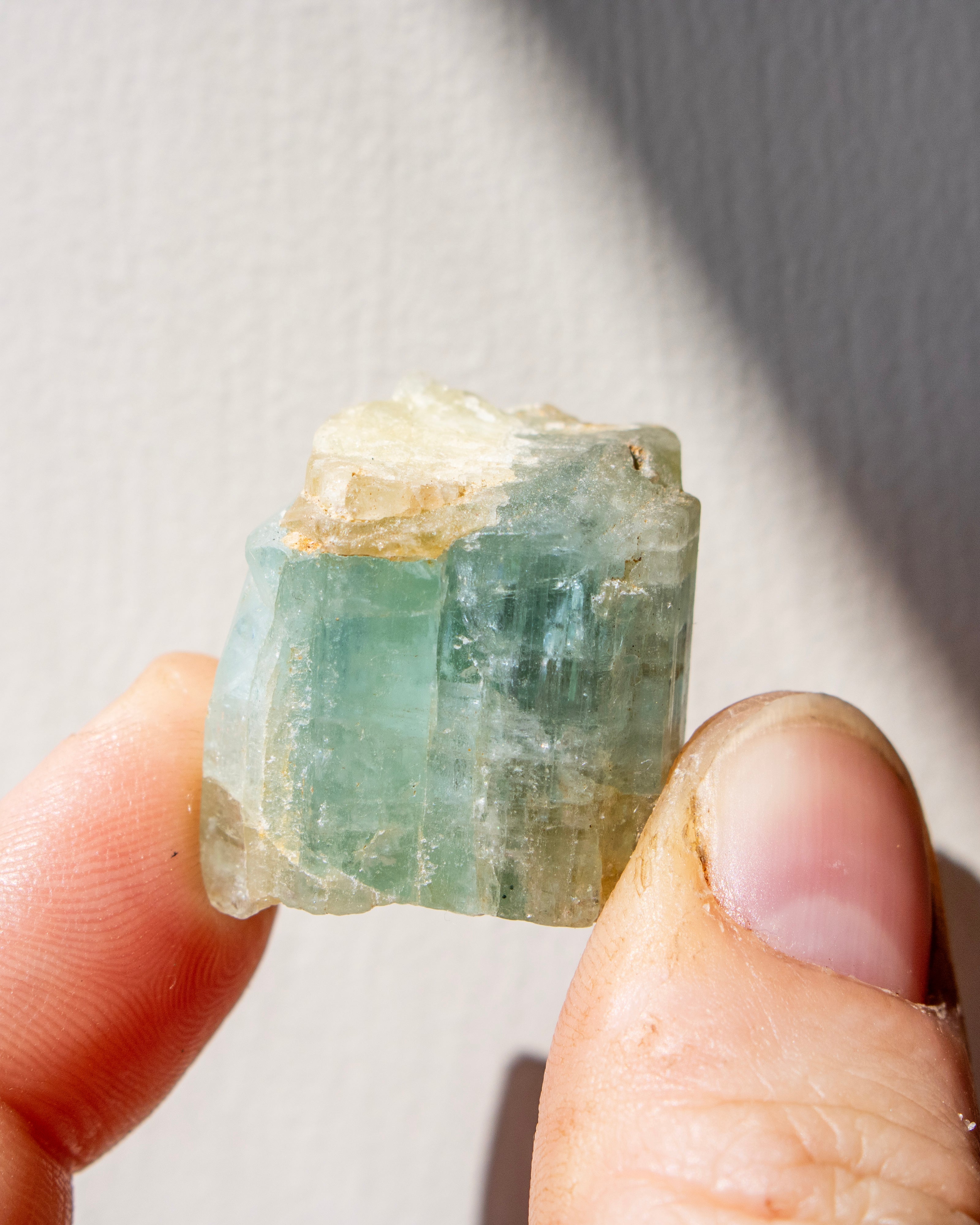 Clear gemstone held between fingers on a neutral background