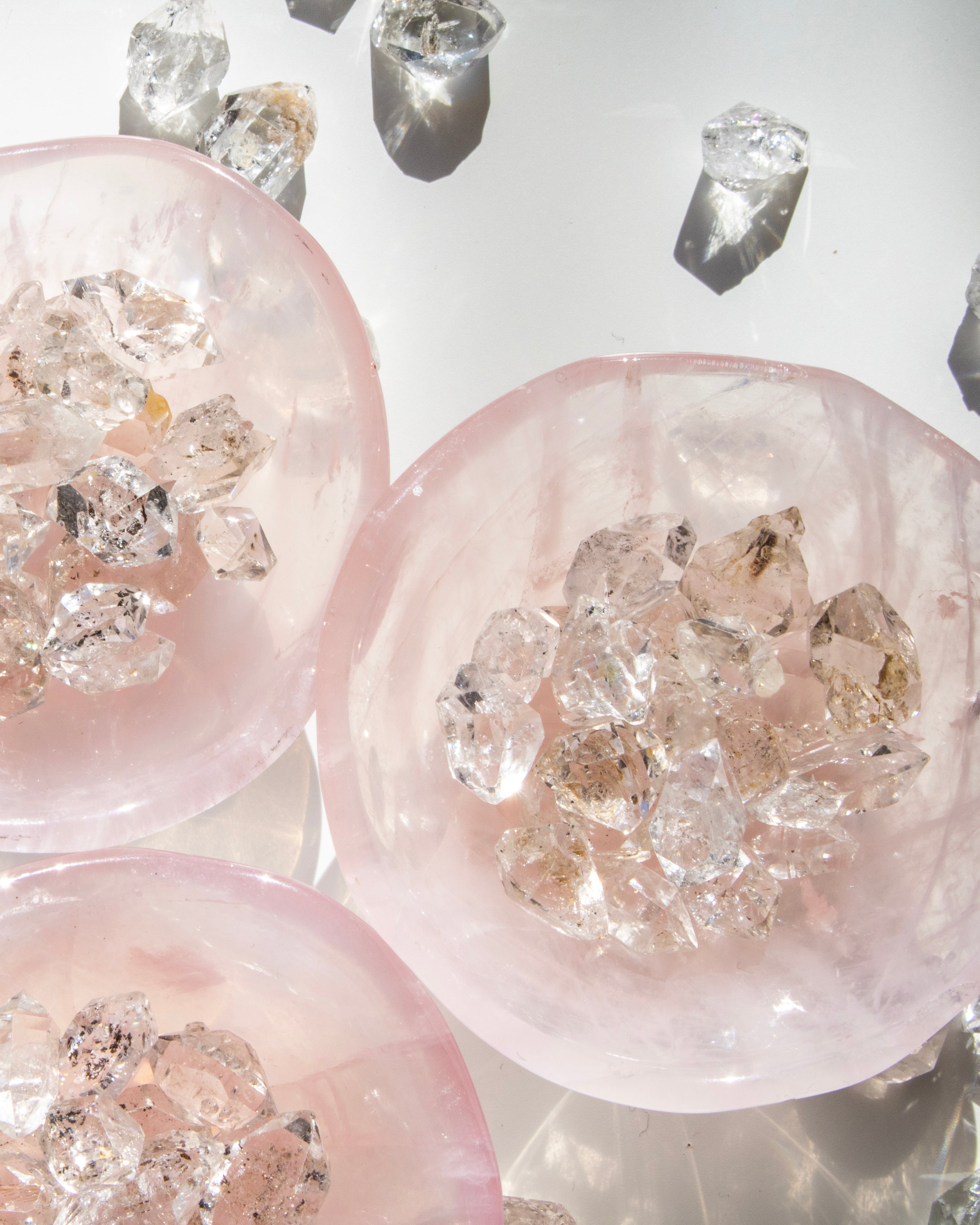 Close-up of rose quartz crystal with embedded clear crystals on a light gray background