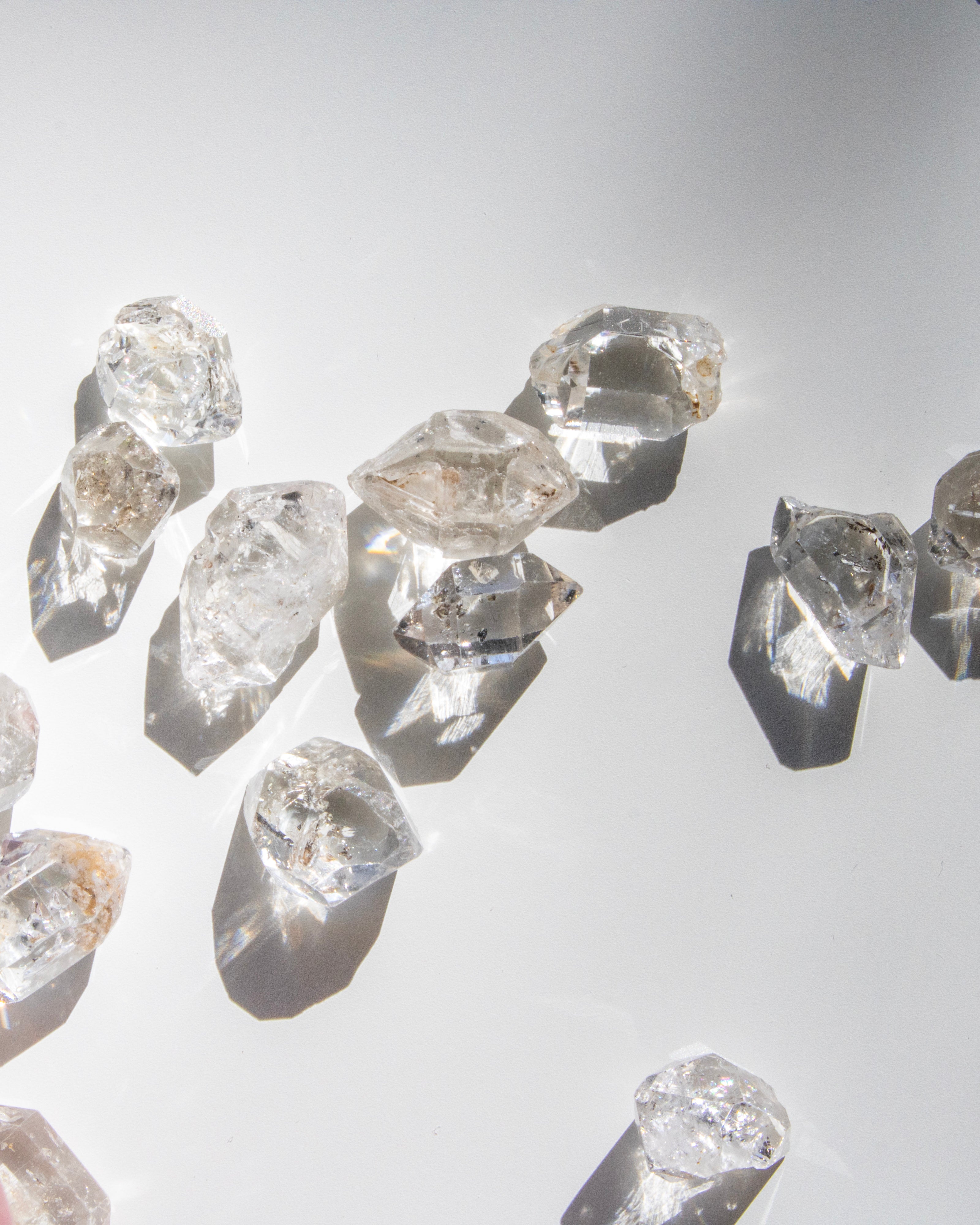 Raw diamonds scattered on a reflective surface with a light gray background